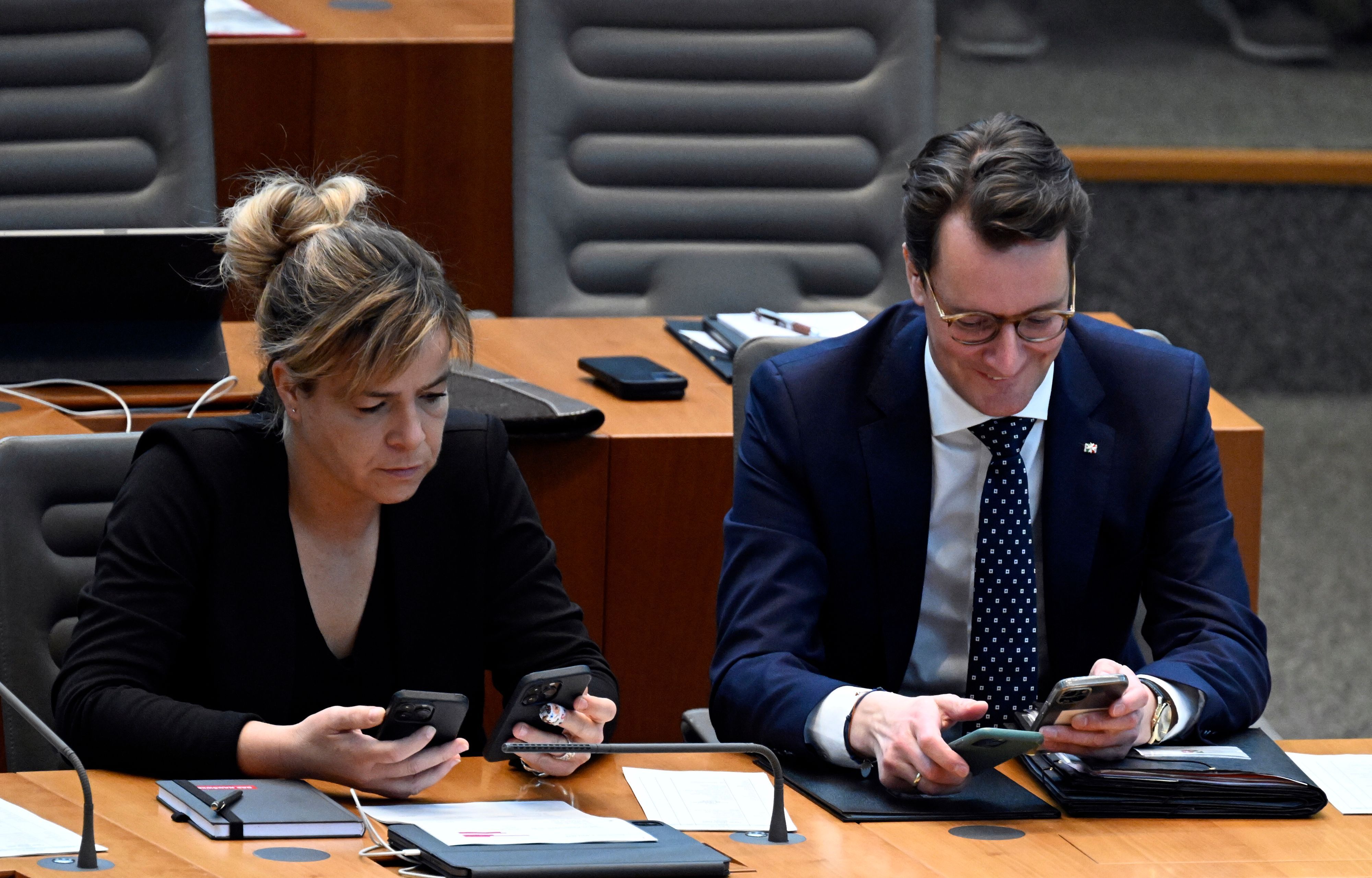 Hendrik Wüst (CDU), Ministerpräsident von Nordrhein-Westfalen, und Mona Neubaur (Bündnis 90/Die Grünen), Ministerin für Wirtschaft, Industrie, Klimaschutz und Energie von Nordrhein-Westfalen, schauen im Landtag auf ihre Handys.