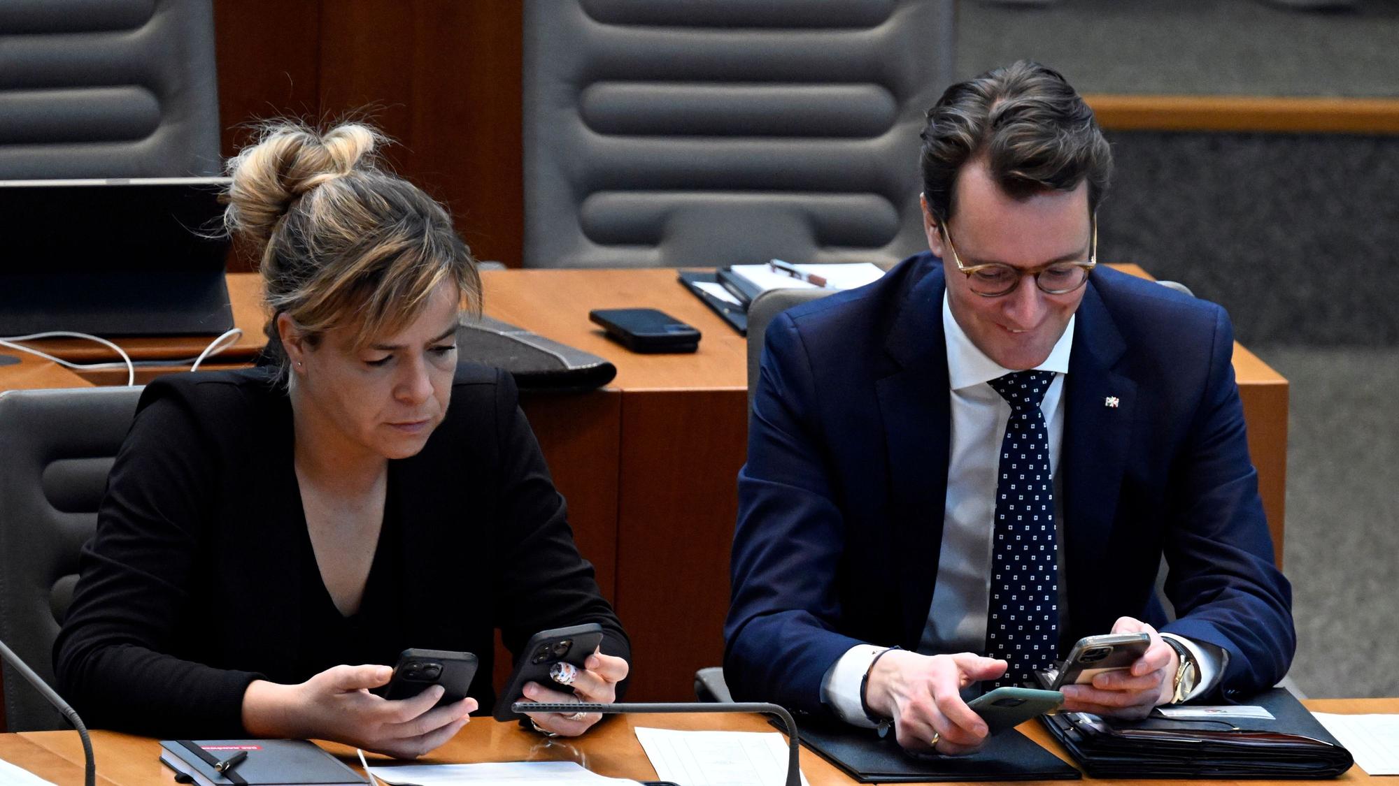 Hendrik Wüst (CDU), Ministerpräsident von Nordrhein-Westfalen, und Mona Neubaur (Bündnis 90/Die Grünen), Ministerin für Wirtschaft, Industrie, Klimaschutz und Energie von Nordrhein-Westfalen, schauen im Landtag auf ihre Handys.