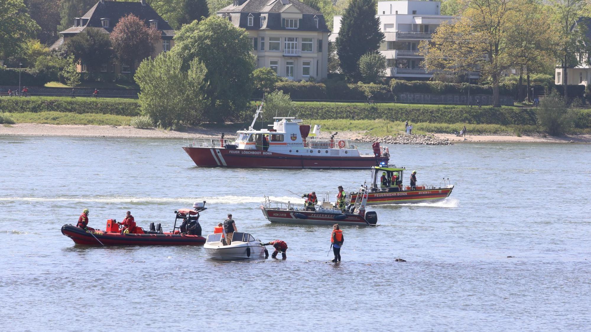Mehrere Schiffe, darunter Feuerwehrboote auf dem Rhein neben einem kleinen Sportboot.
