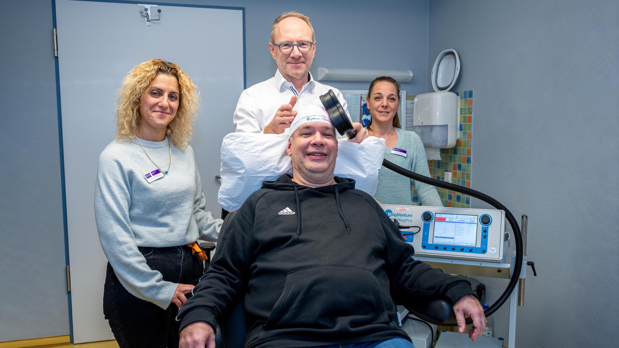 Ein Arzt legt einem Patienten eine Magnetspule auf den Kopf.