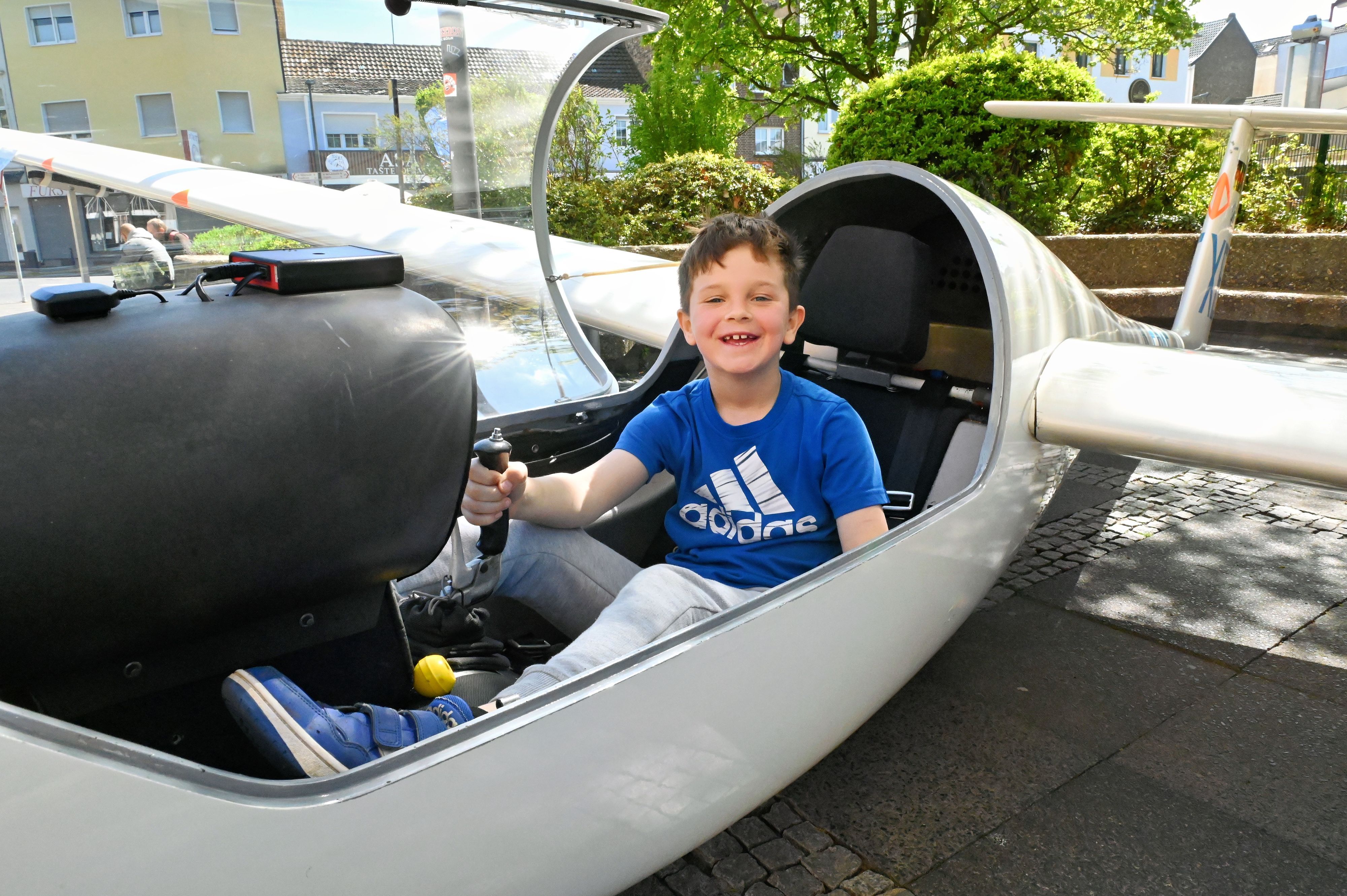 Leo hat im Cockpit des Segelflugzeuges Platz genommen und hält den Steuerknüppel in der Hand.