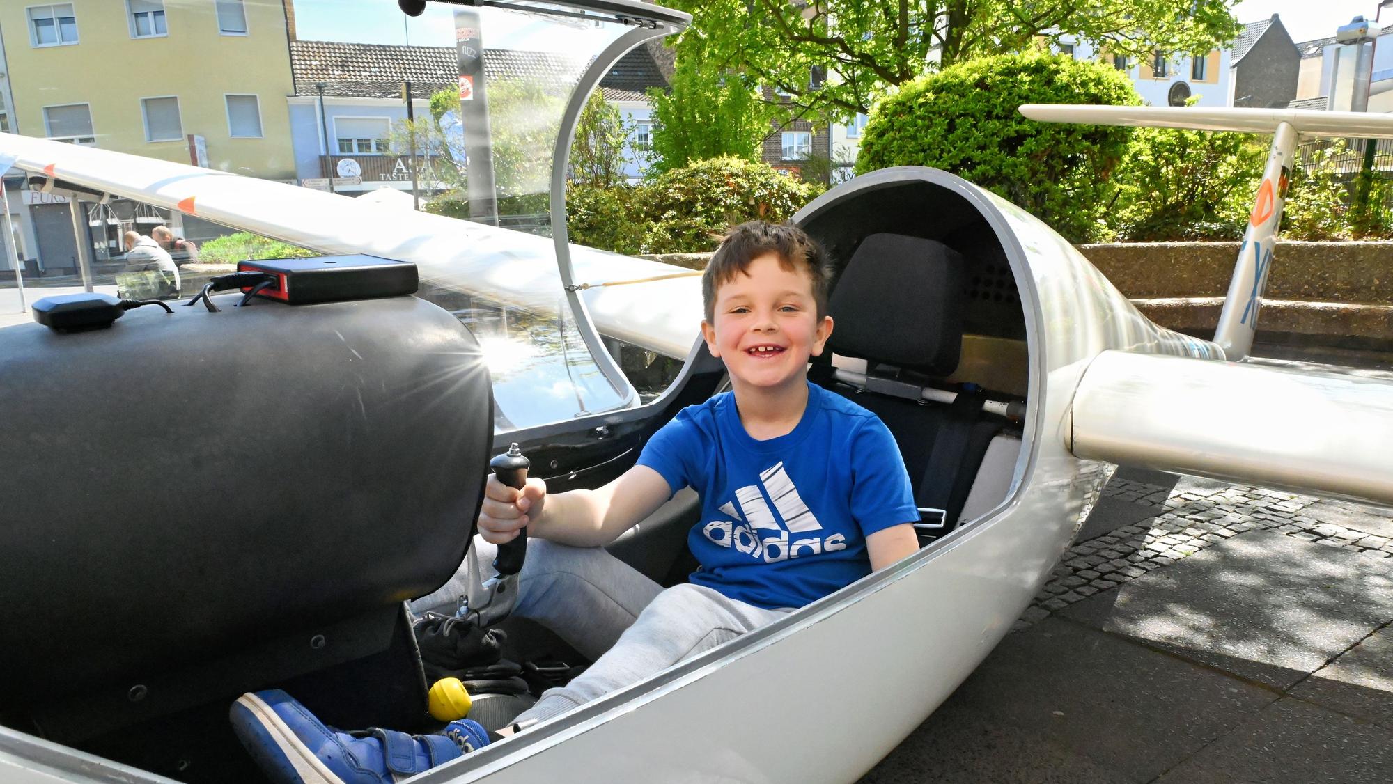 Leo hat im Cockpit des Segelflugzeuges Platz genommen und hält den Steuerknüppel in der Hand.