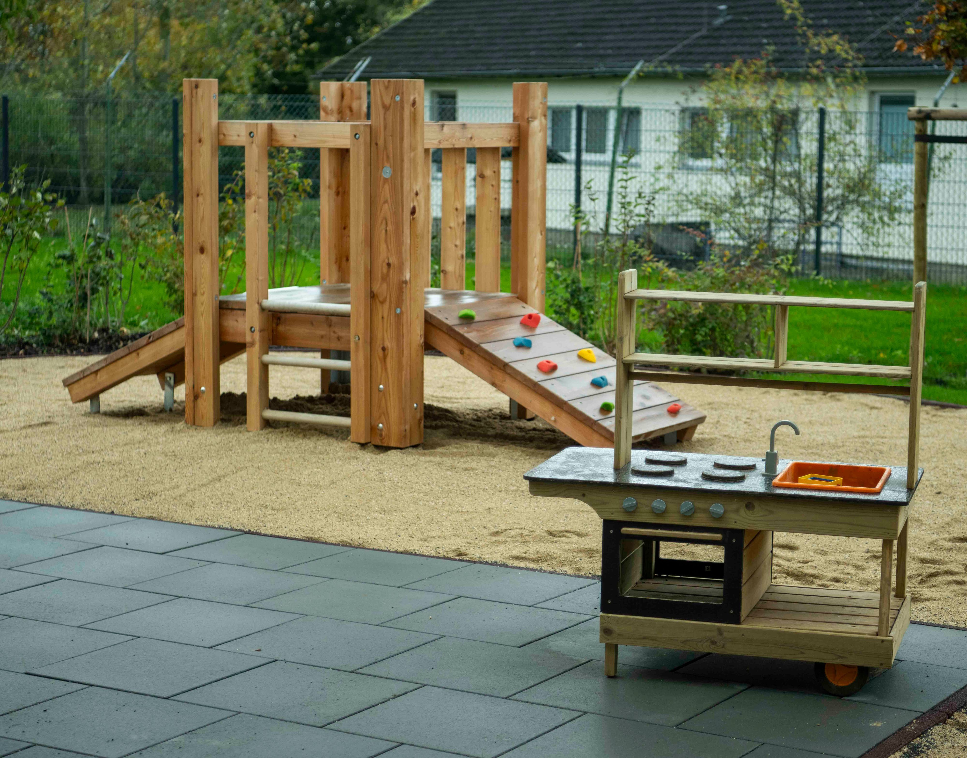 Eine Spielküche und ein Klettergerüst im Außenbereich einer Kita.