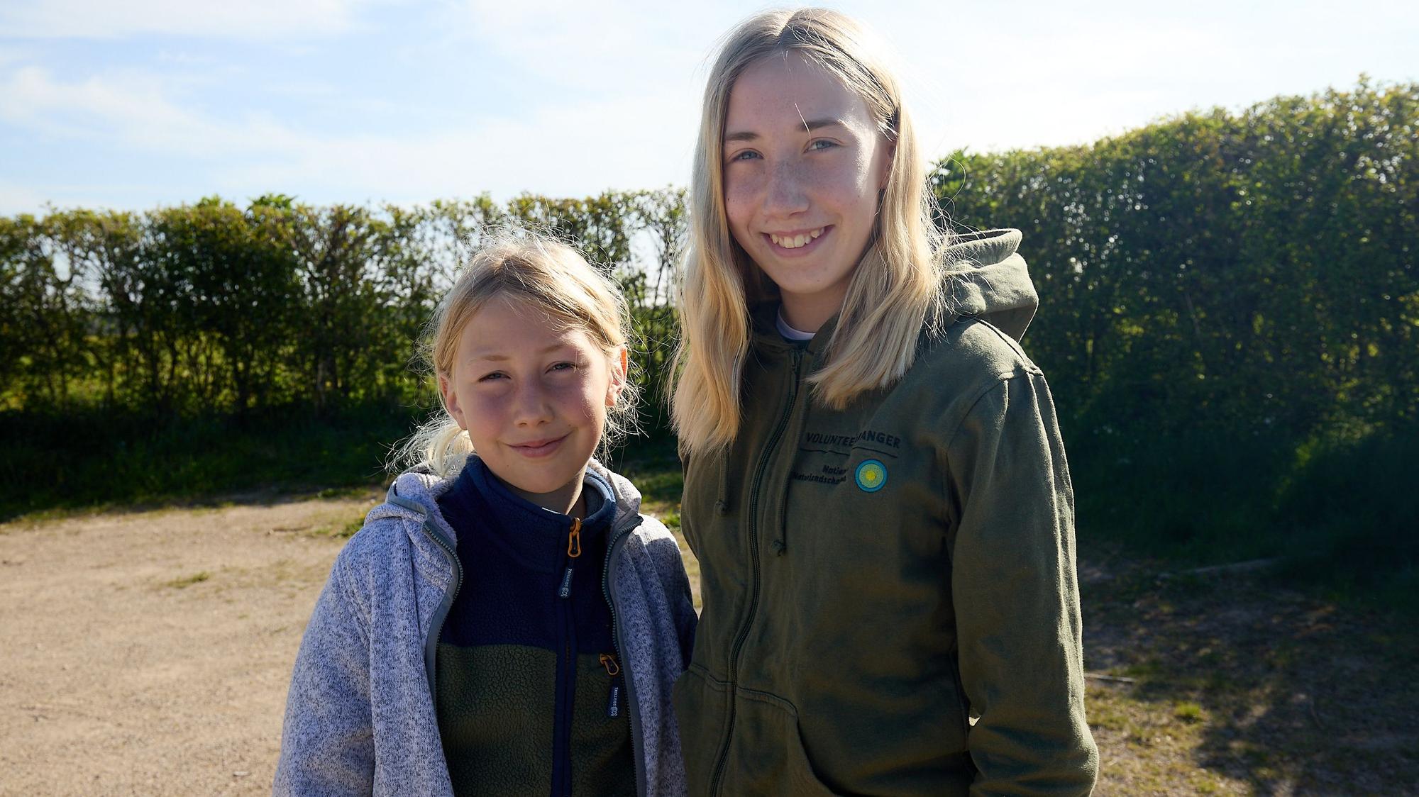 Beide Geschwister haben blonde Haare und schauen lächelnd in die Kamera.