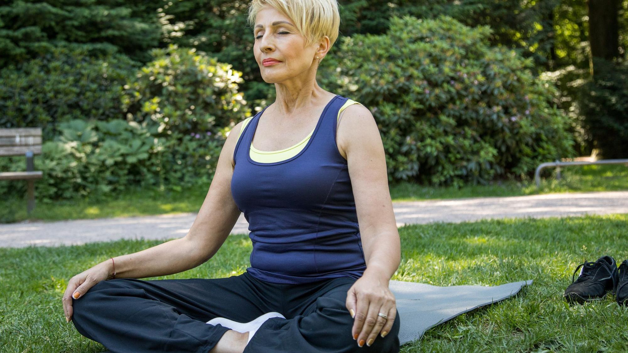 Frau macht Yoga-Übungen im Park