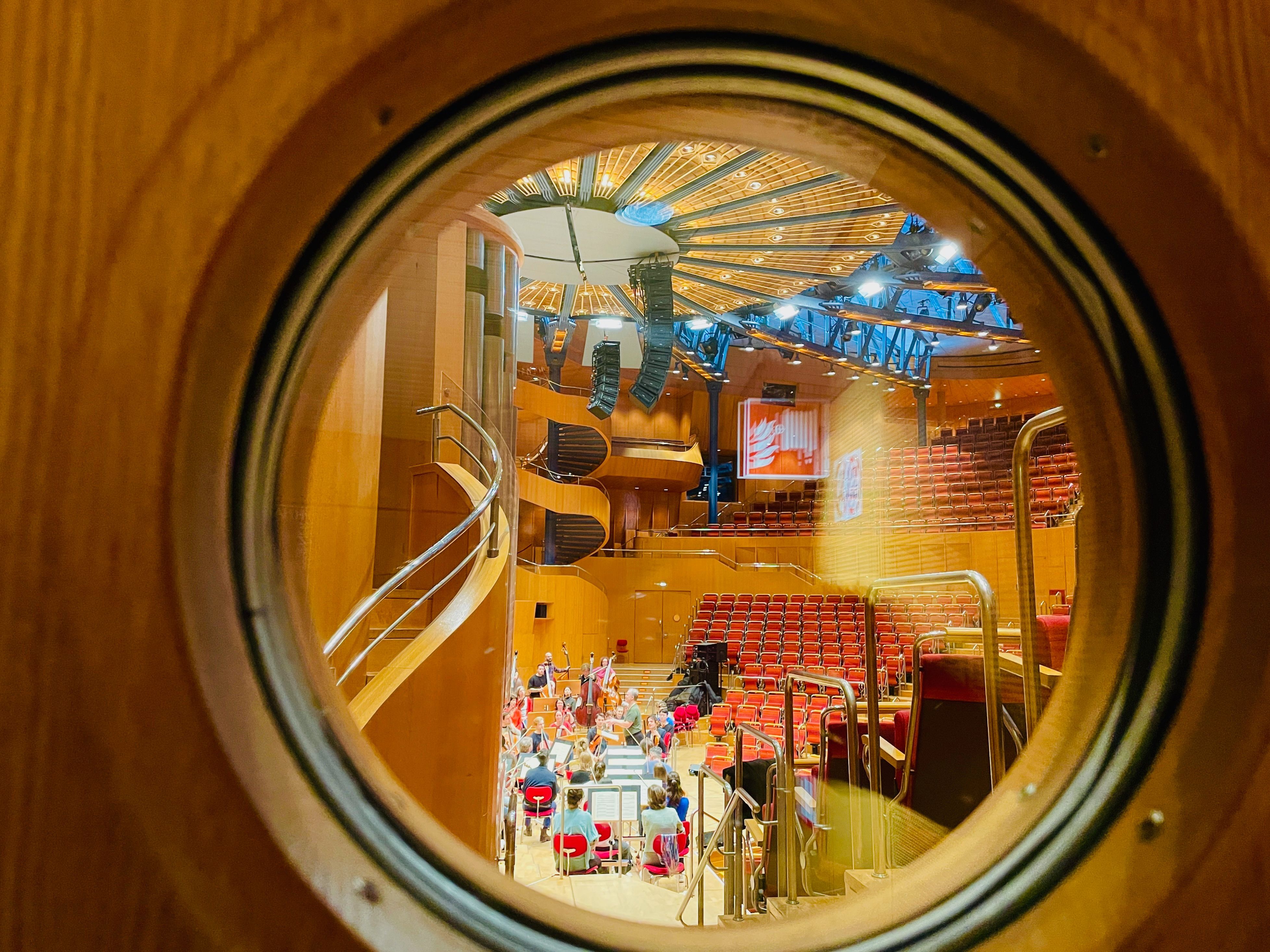 Blick in den Konzertsaal der Philharmonie durch ein rundes Fenster