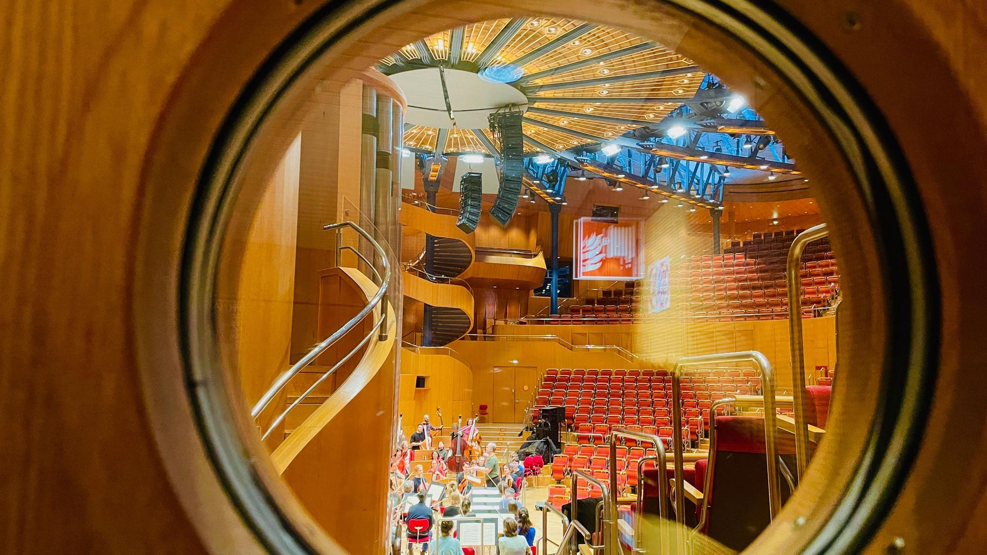 Blick in den Konzertsaal der Philharmonie durch ein rundes Fenster