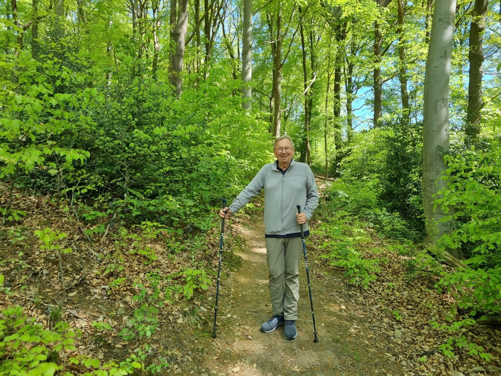 Bernd Stelter steht mit Wanderstöcken im Wald.