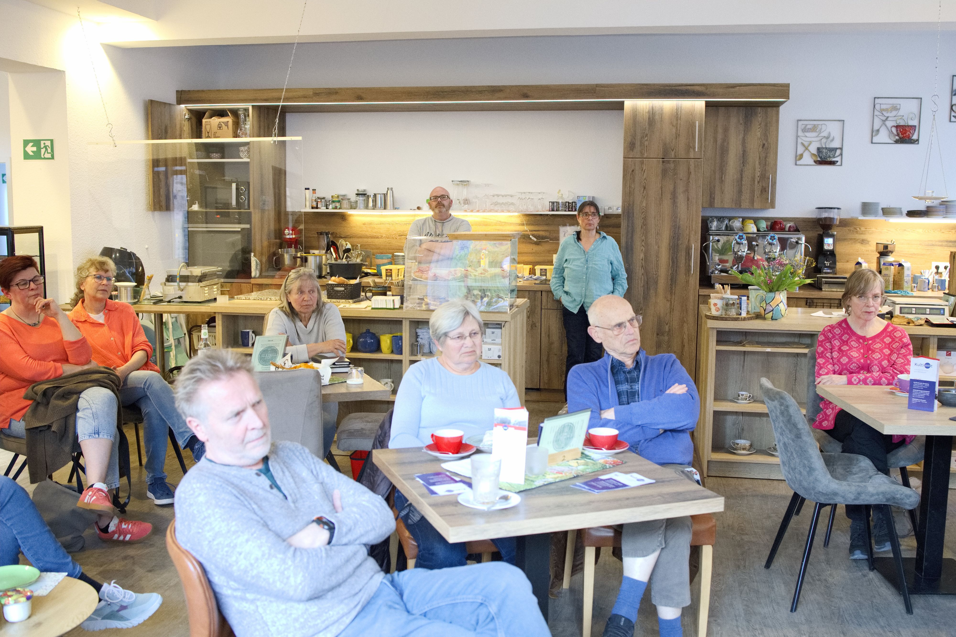 Besucher des Gesprächsabends zur Flutkatastrophe sitzen im Tee- und Kaffeehaus in Bad Münstereifel an Tischen.