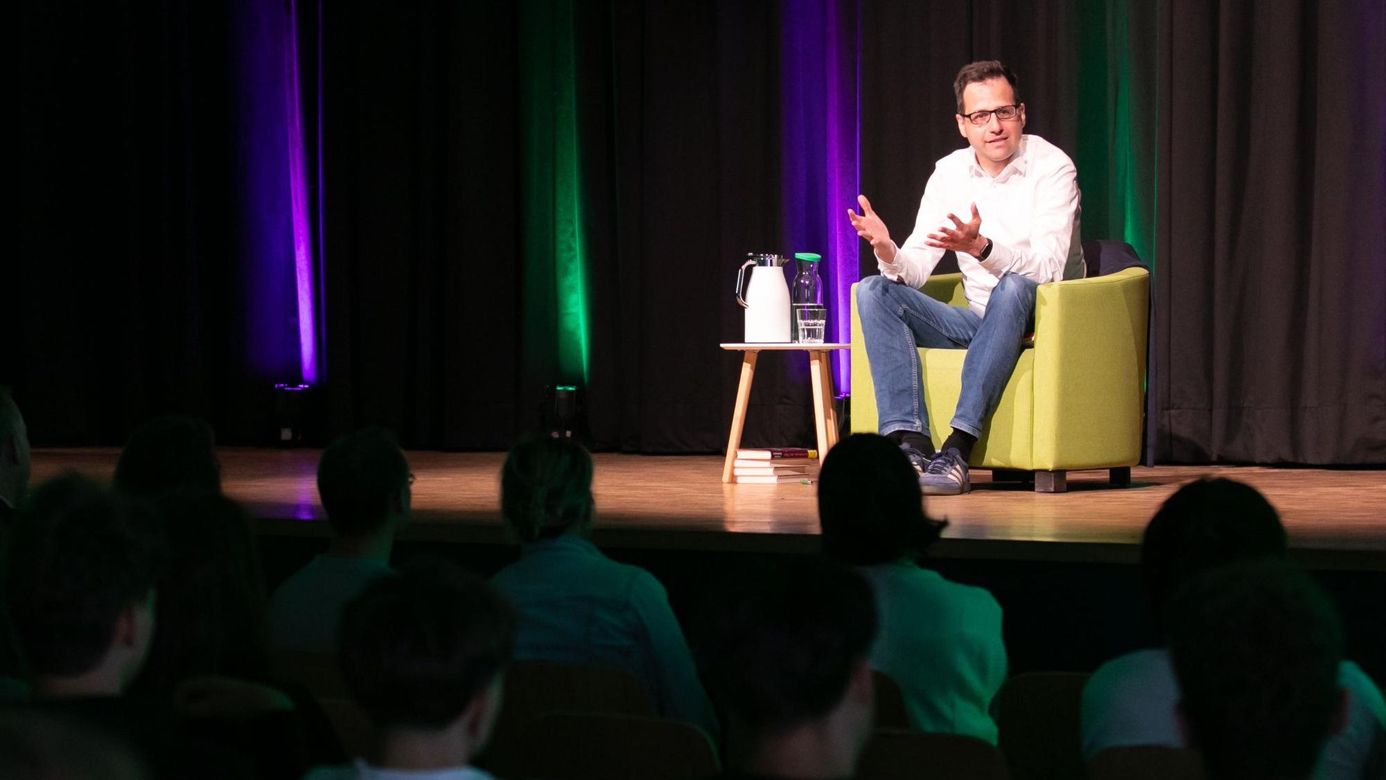Das Foto zeigt Lorenz Hemicker auf der Bühne der Aula des Lindengymnasiums.