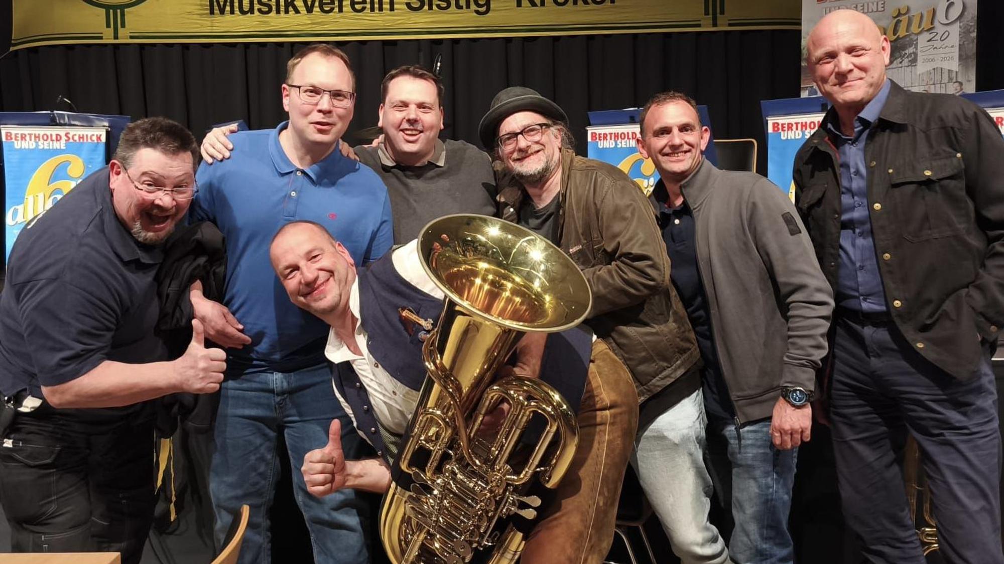 Das Foto zeigt die Bandmitglieder, einer hält eine Tuba.