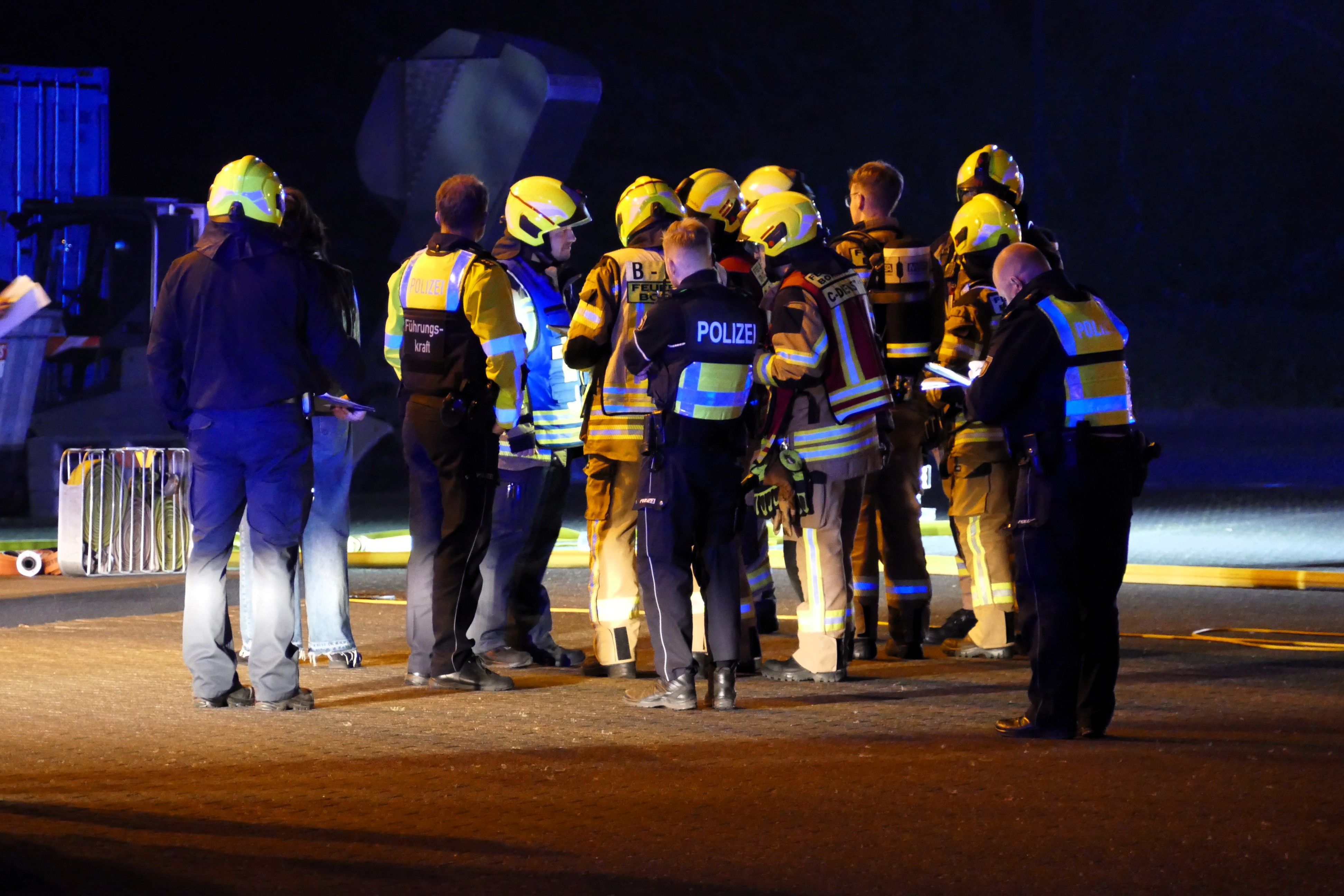 Feuerwehrleute und Polizeibeamte beraten das weitere Vorgehen.