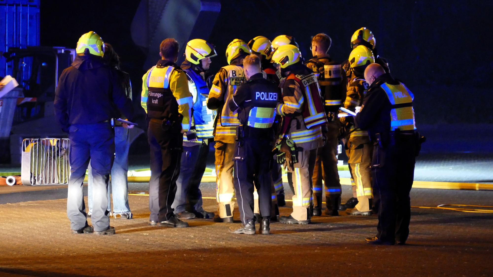 Feuerwehrleute und Polizeibeamte beraten das weitere Vorgehen.