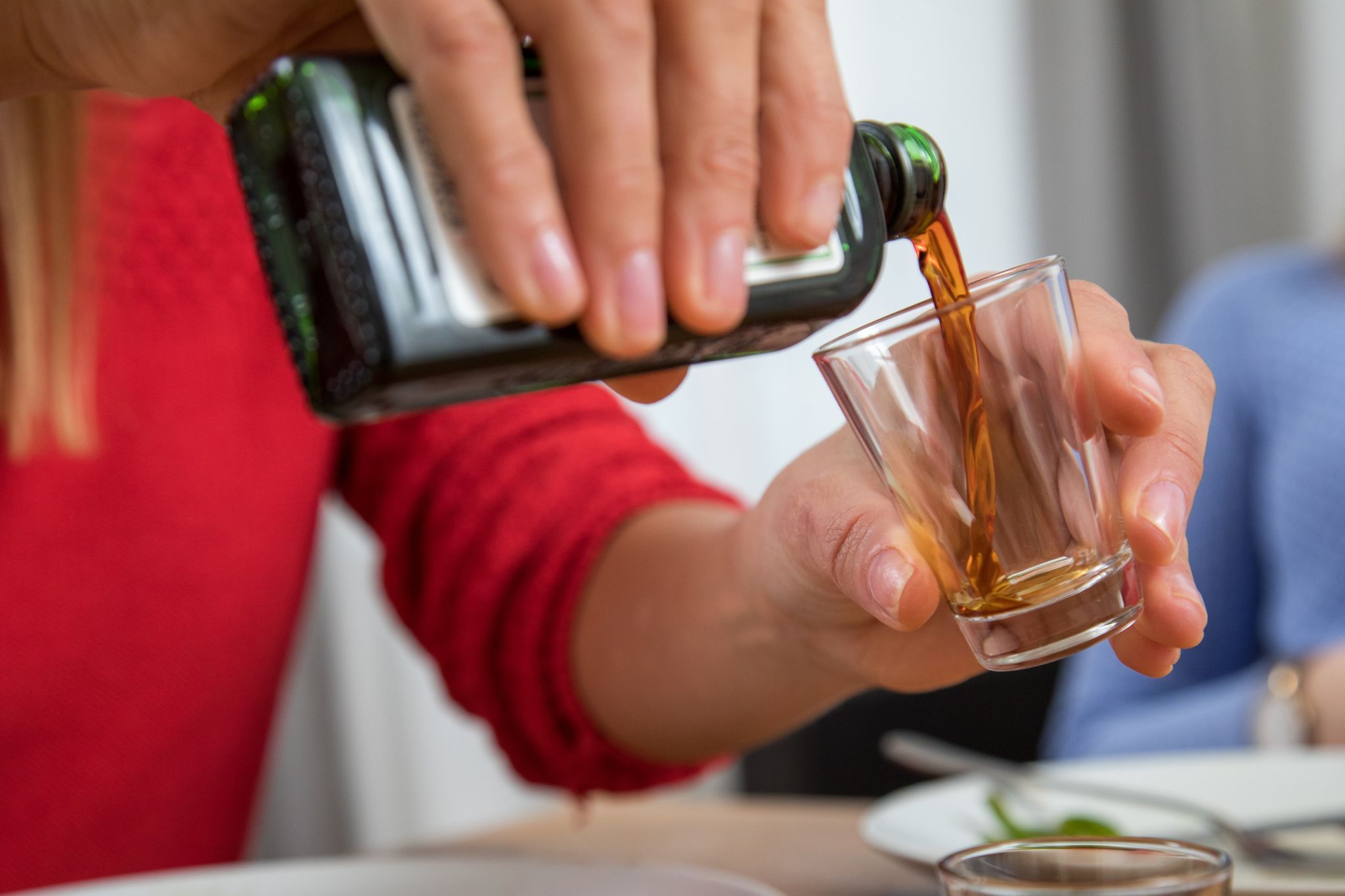 Frau schenkt ein Glas Schnaps ein