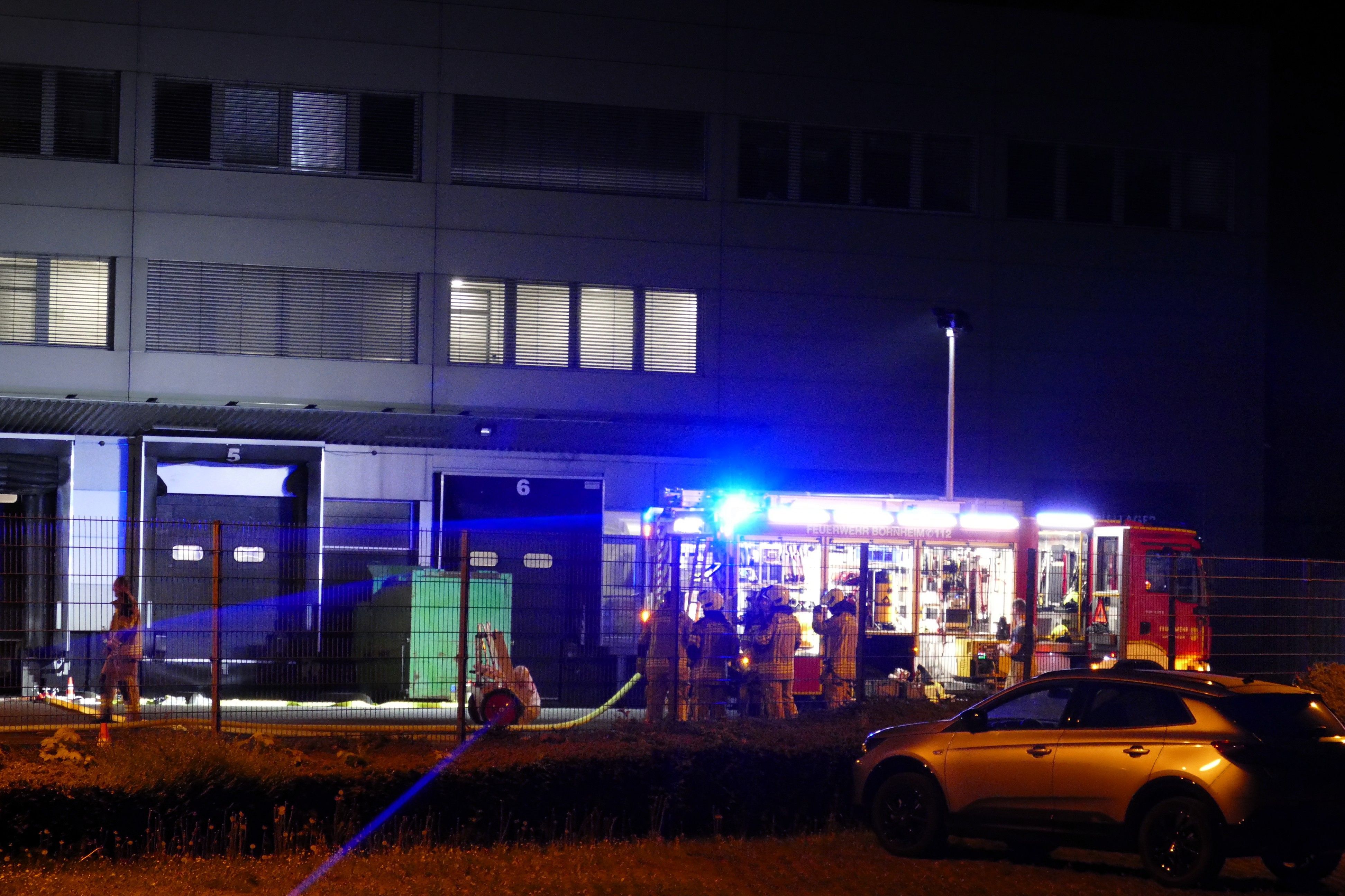 Feuerwehrleute stehen auf dem Firmengelände des fleischverarbeitenden Betriebs.