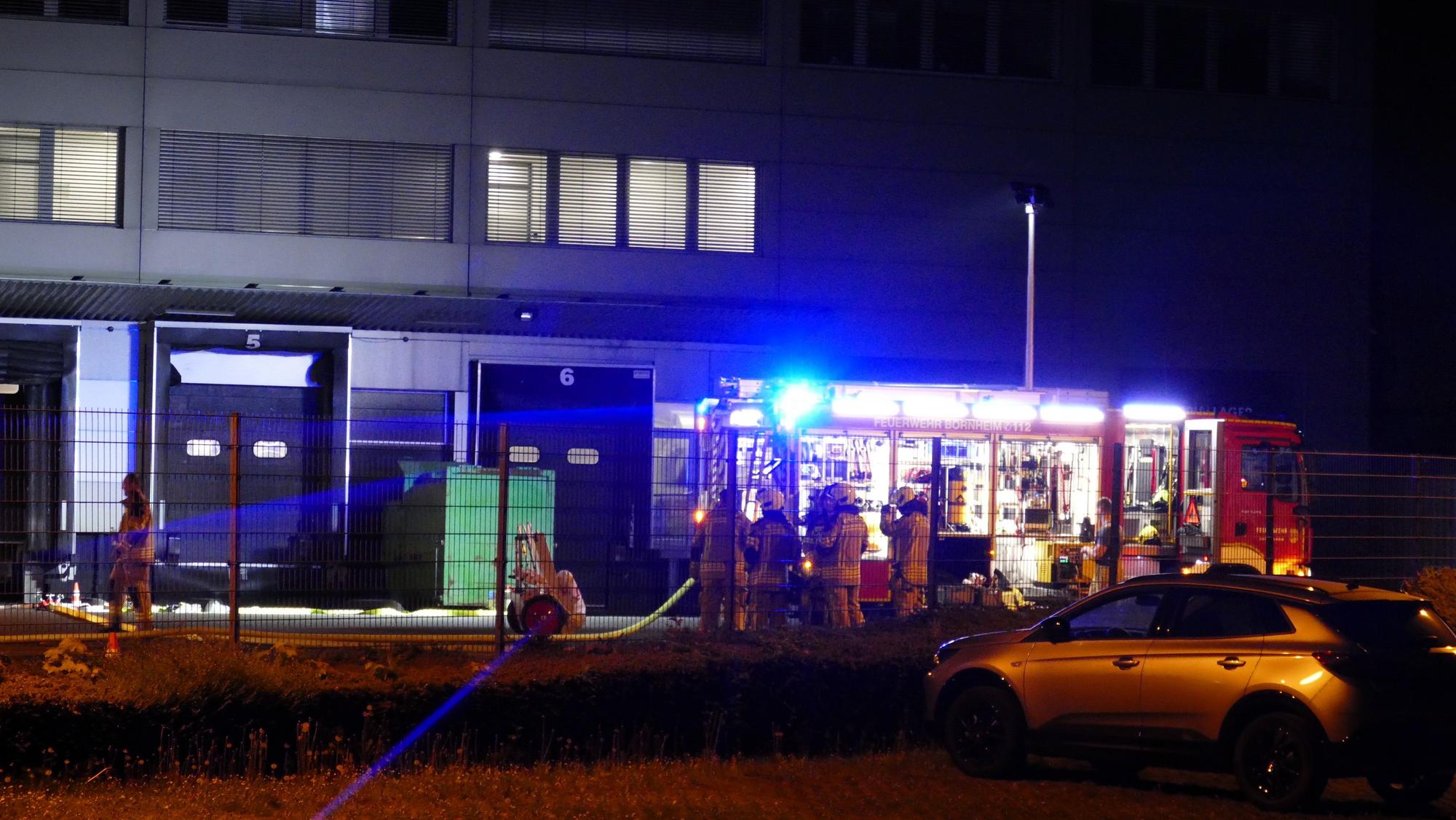 Feuerwehrleute stehen auf dem Firmengelände des fleischverarbeitenden Betriebs.