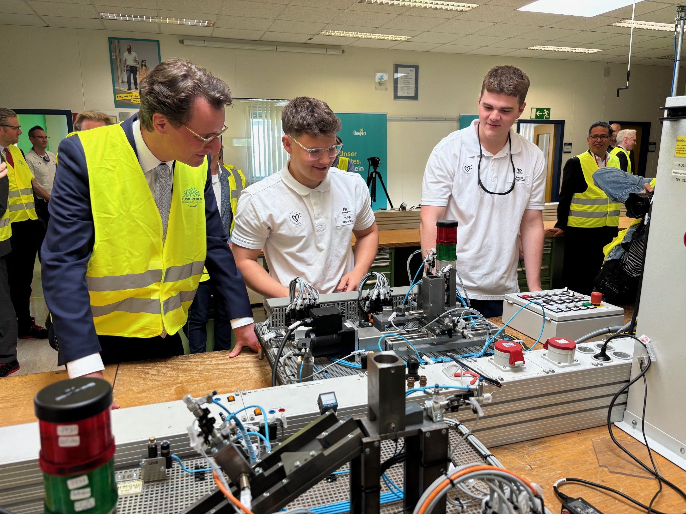 Zwei Auszubildende demonstrieren Hendrik Wüst im Procter & Gamble-Werk Euskirchen technisches Equipment.