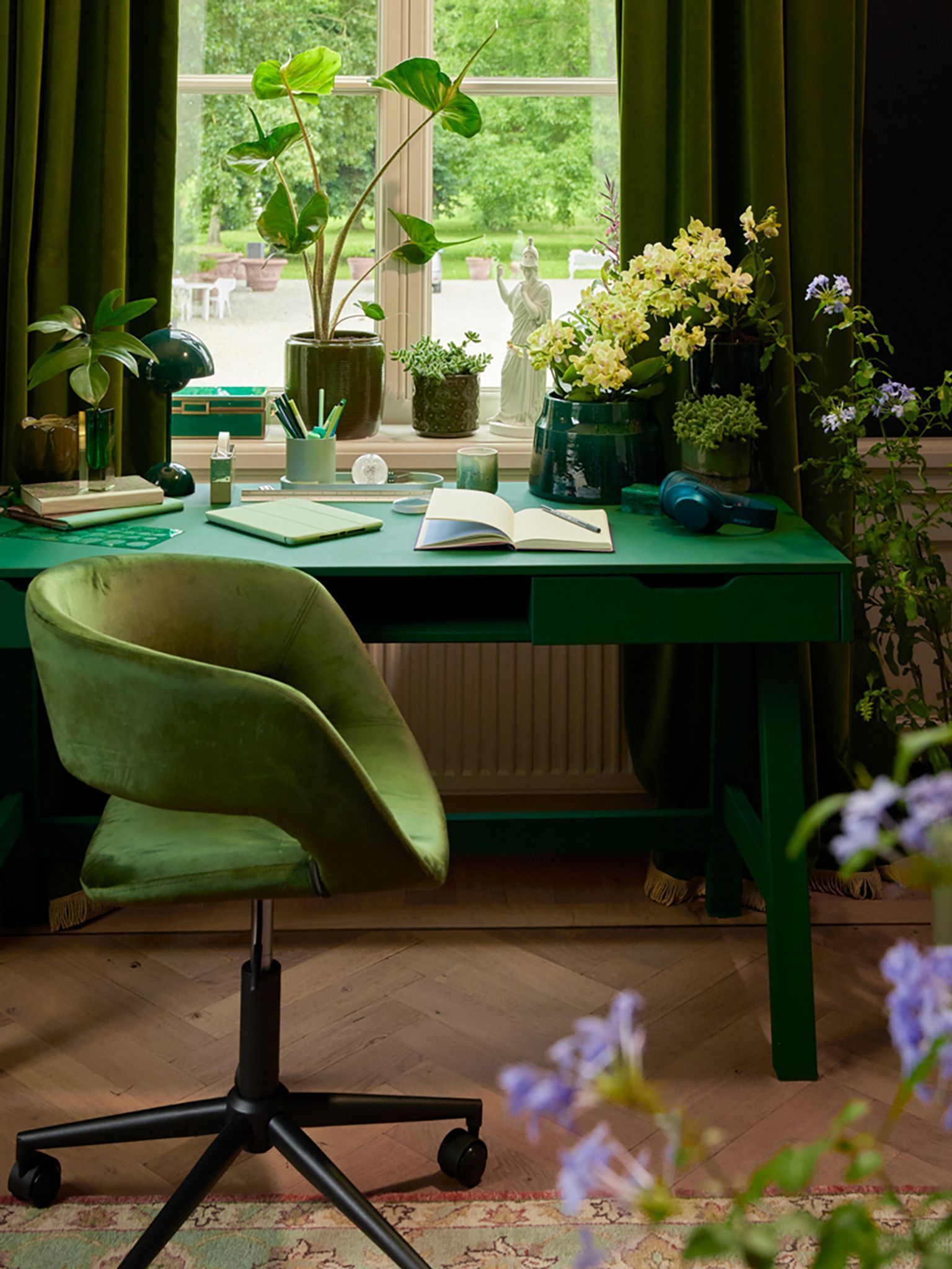 Viele Grünenpflanzen stehen neben einem Schreibtisch
