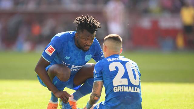 Alex Grimaldo Bayer Leverkusen sitzt am Boden, Edmond Tapsoba Bayer Leverkusen sieht nach ihm, Verletzung. Fussball 1. Bundesliga, 31.Spieltag, 1. FC Koeln - Bayer 04 Leverkusen. 1:2, am 25.04.2026 in Koeln/ Deutschland. DFL regulations prohibit any use of photographs as image sequences and/or quasi-video  *** Alex Grimaldo Bayer Leverkusen sits on the ground, Edmond Tapsoba Bayer Leverkusen looks after him, injury Football 1 Bundesliga, Matchday 31, 1 FC Koeln Bayer 04 Leverkusen 1 2, on 25 04 2026 in Koeln Germany DFL regulations prohibit any use of photographs as image sequences and or quasi video Â