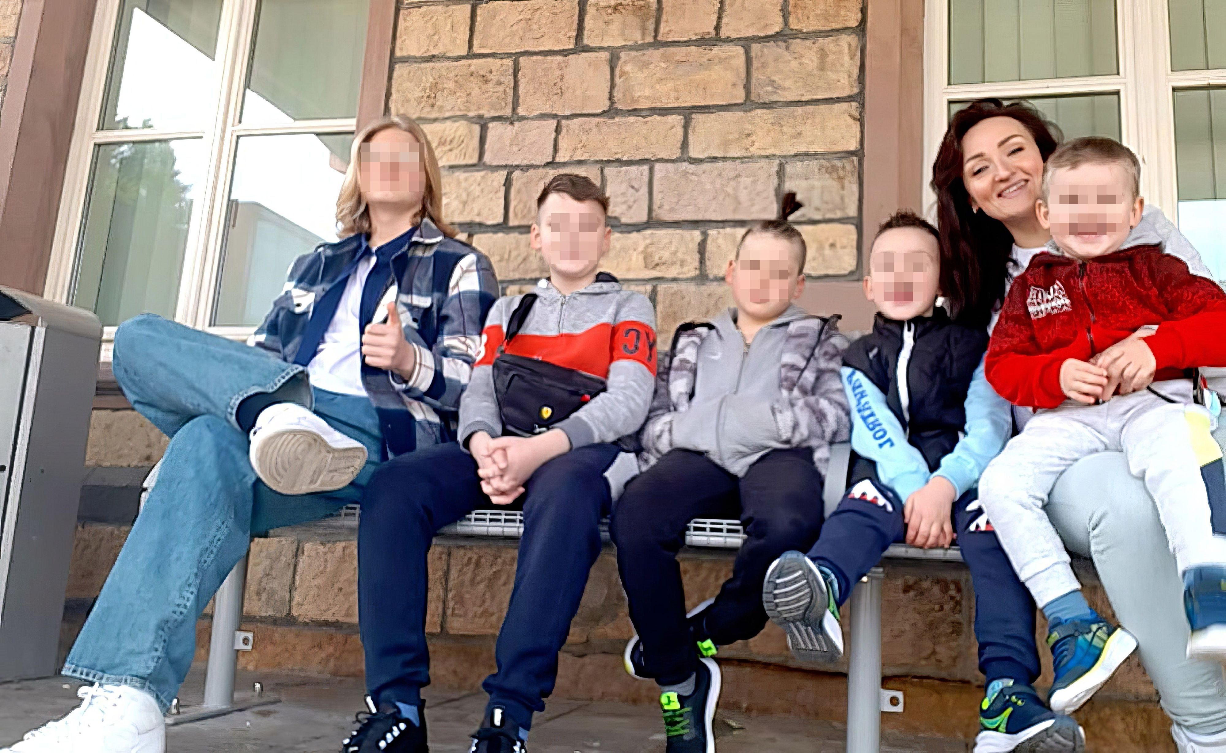 Die fünf Söhne und ihre Mutter sitzen auf einer Bank.