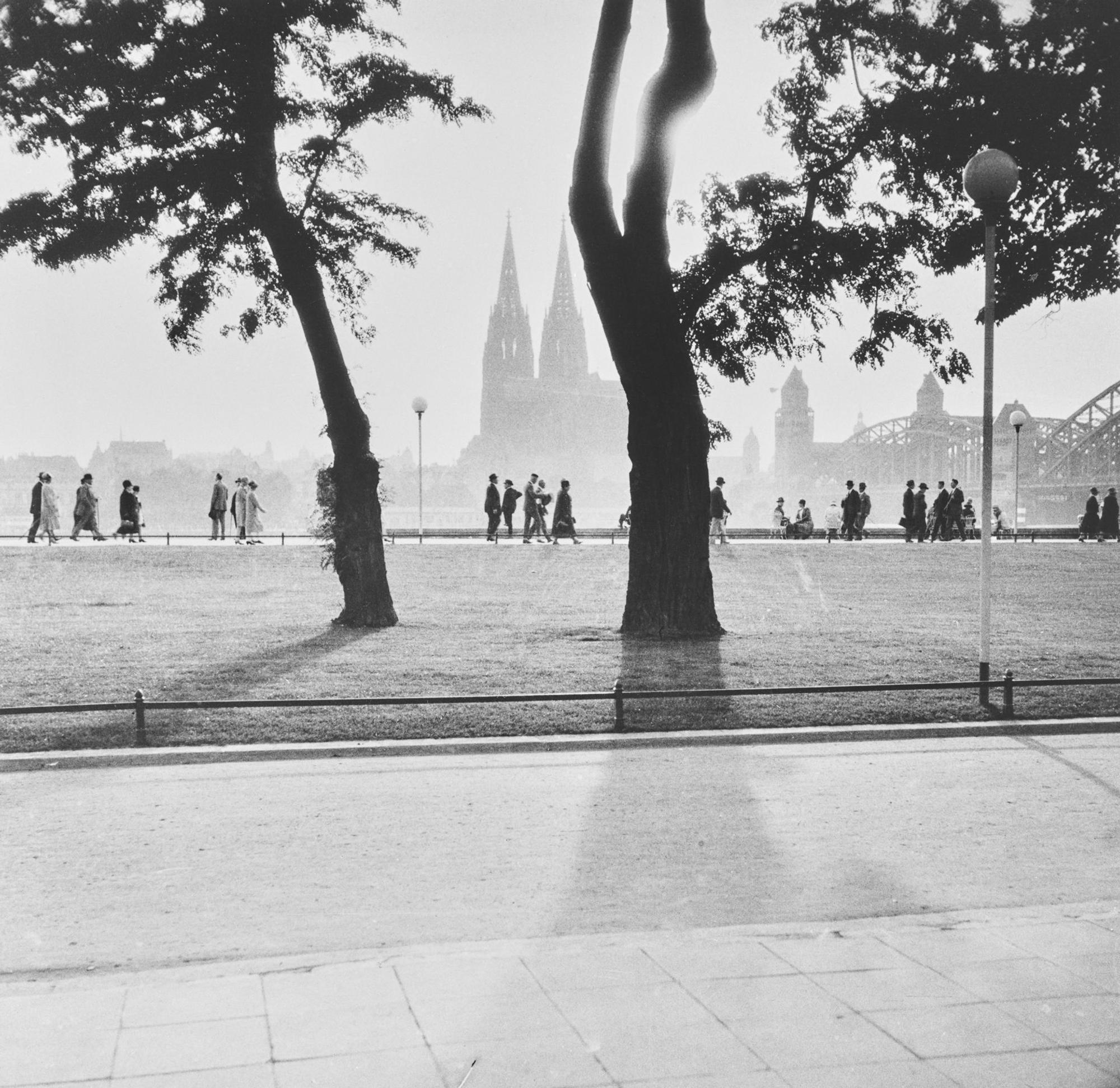 Menschen gehen in Köln am Rheinufer spazieren.