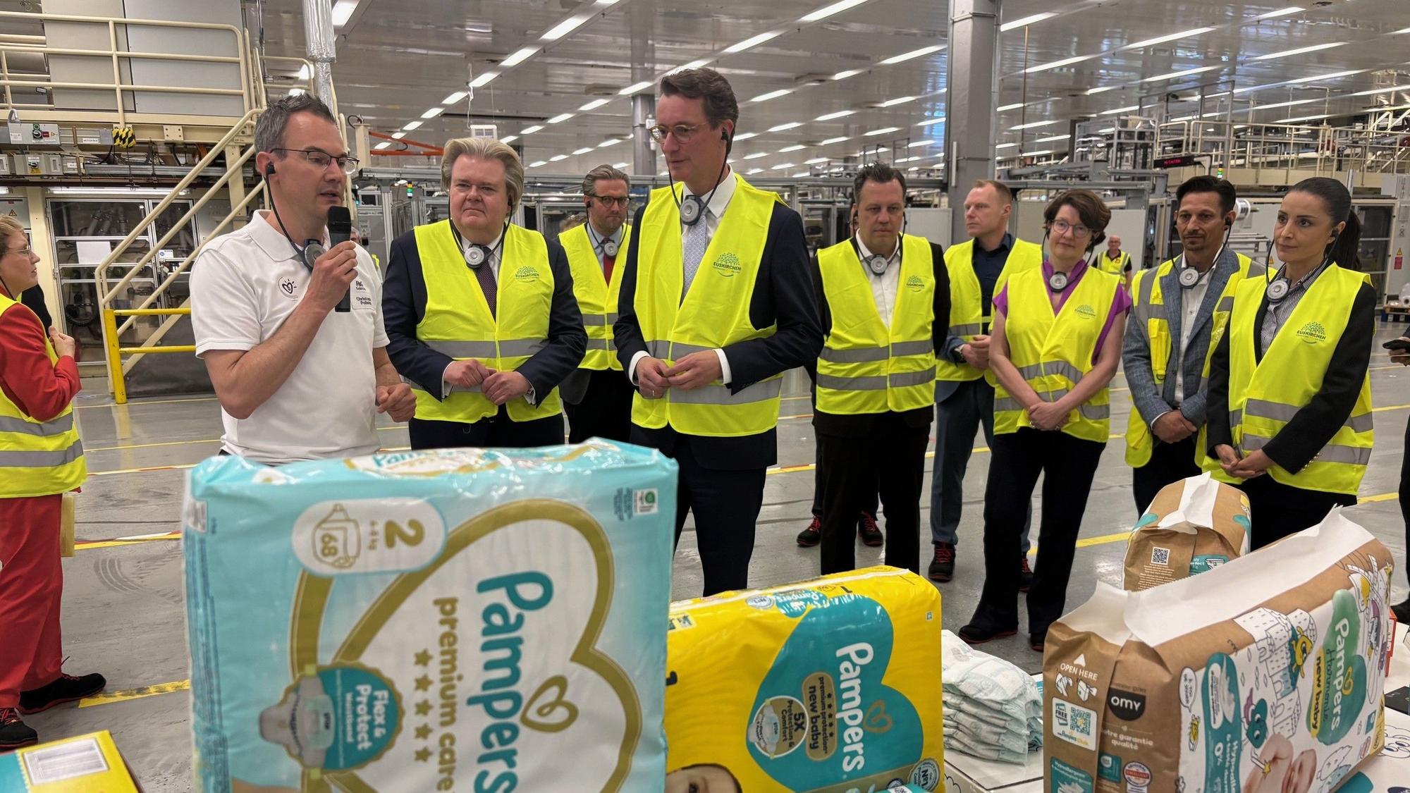 Hendrik Wüst mit einer Besuchergruppe bei der Führung im Procter & Gamble-Werk Euskirchen.