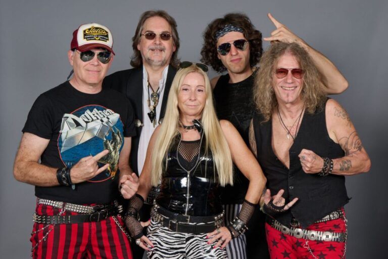 Die Musiker posieren in 80er-/90er-Outfits und blicken in die Kamera.