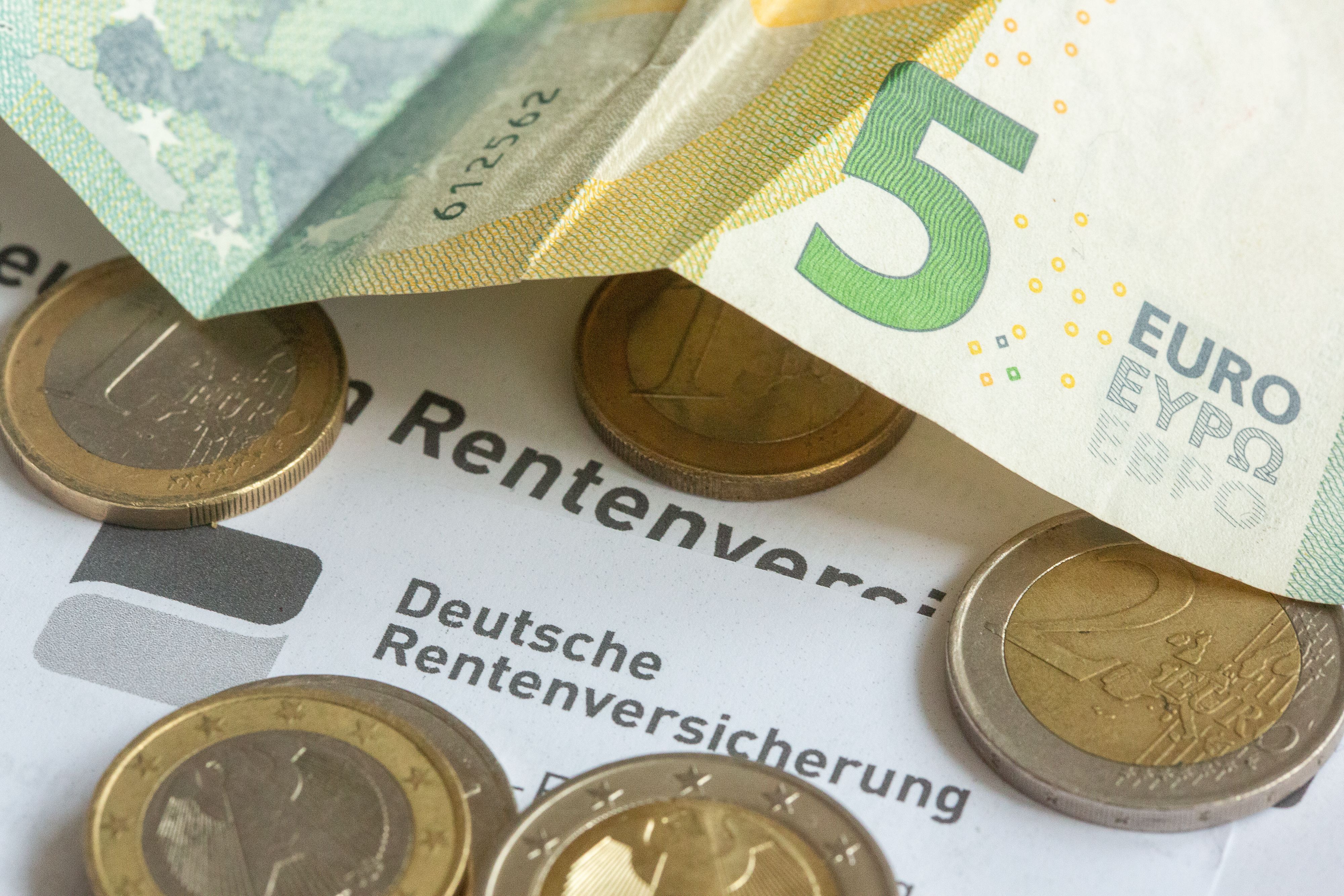 Münzen und eine Banknote liegen auf einer Renteninformation der Deutschen Rentenversicherung. Die Renten steigen um 4,24 Prozent. (Symbolbild)