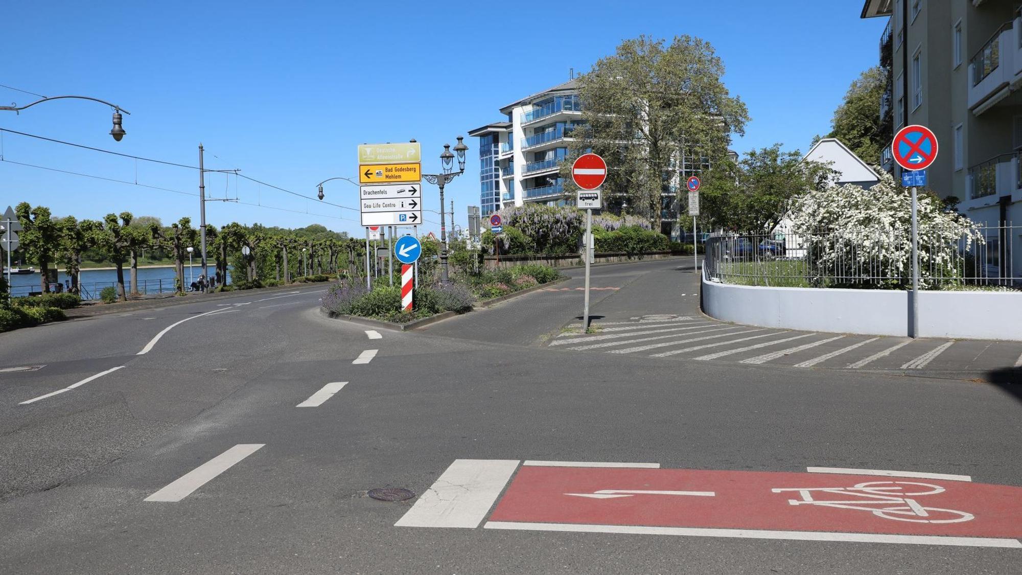 Eine Straßenkreuzung mit einer kurzen Extraspur für Busse, links im Hintergrund die Promenade am Rhein.