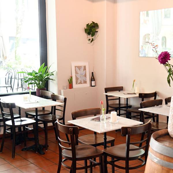 Der Gastraum der Bar mit kleinen Marmor-Tischen und Blumengesteck auf einem Weinfass.