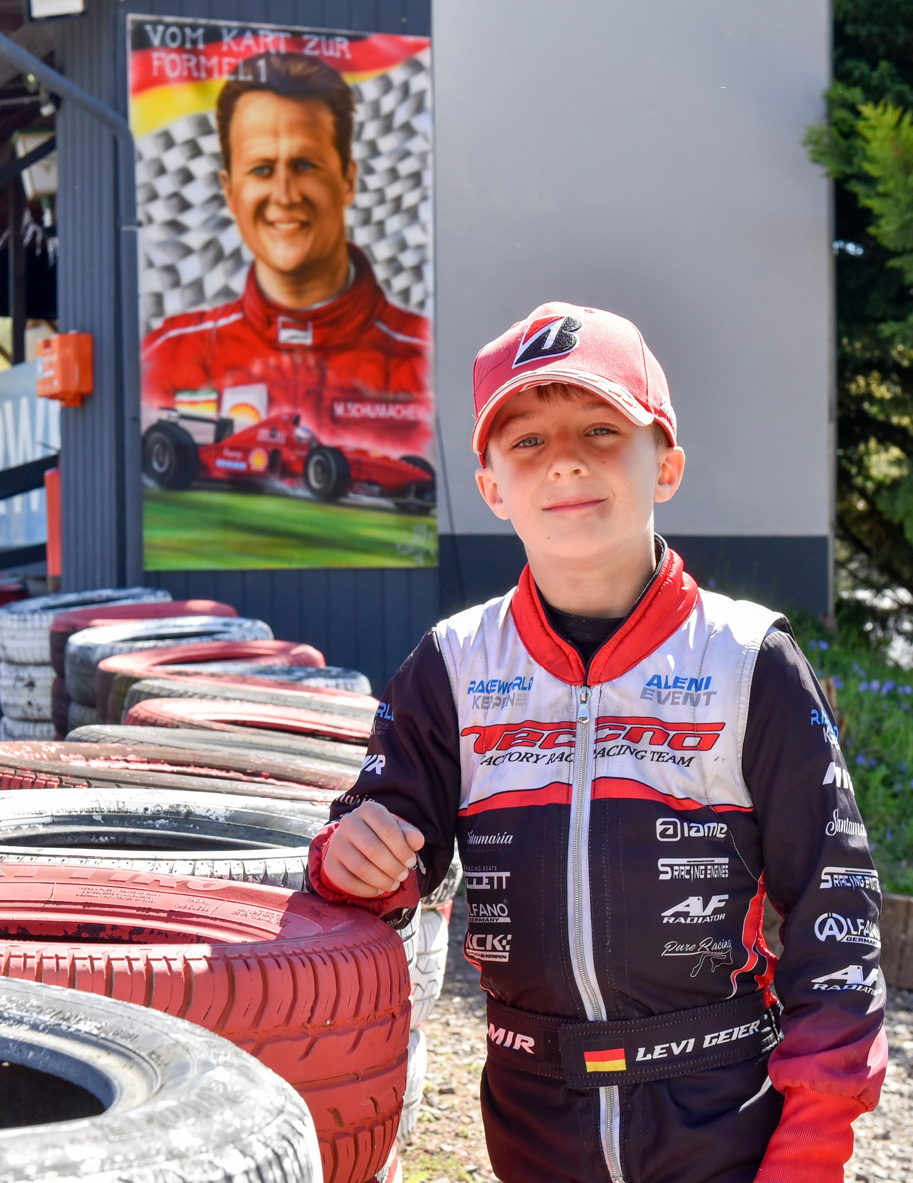 Das Foto zeigt einen Jungen vor einem Plakat von Michael Schumacher.