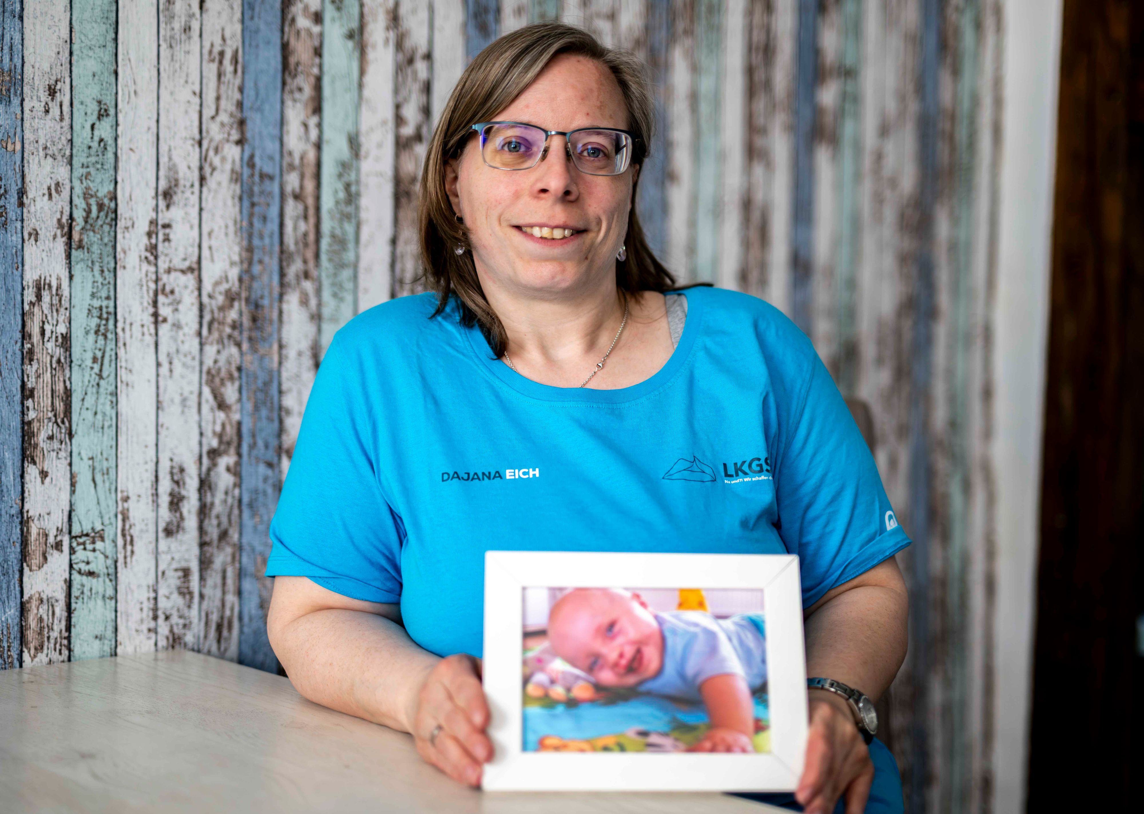 Das Bild zeigt die Großbüllesheimein, die ein Bild von ihrem Baby in die Kamera hält.