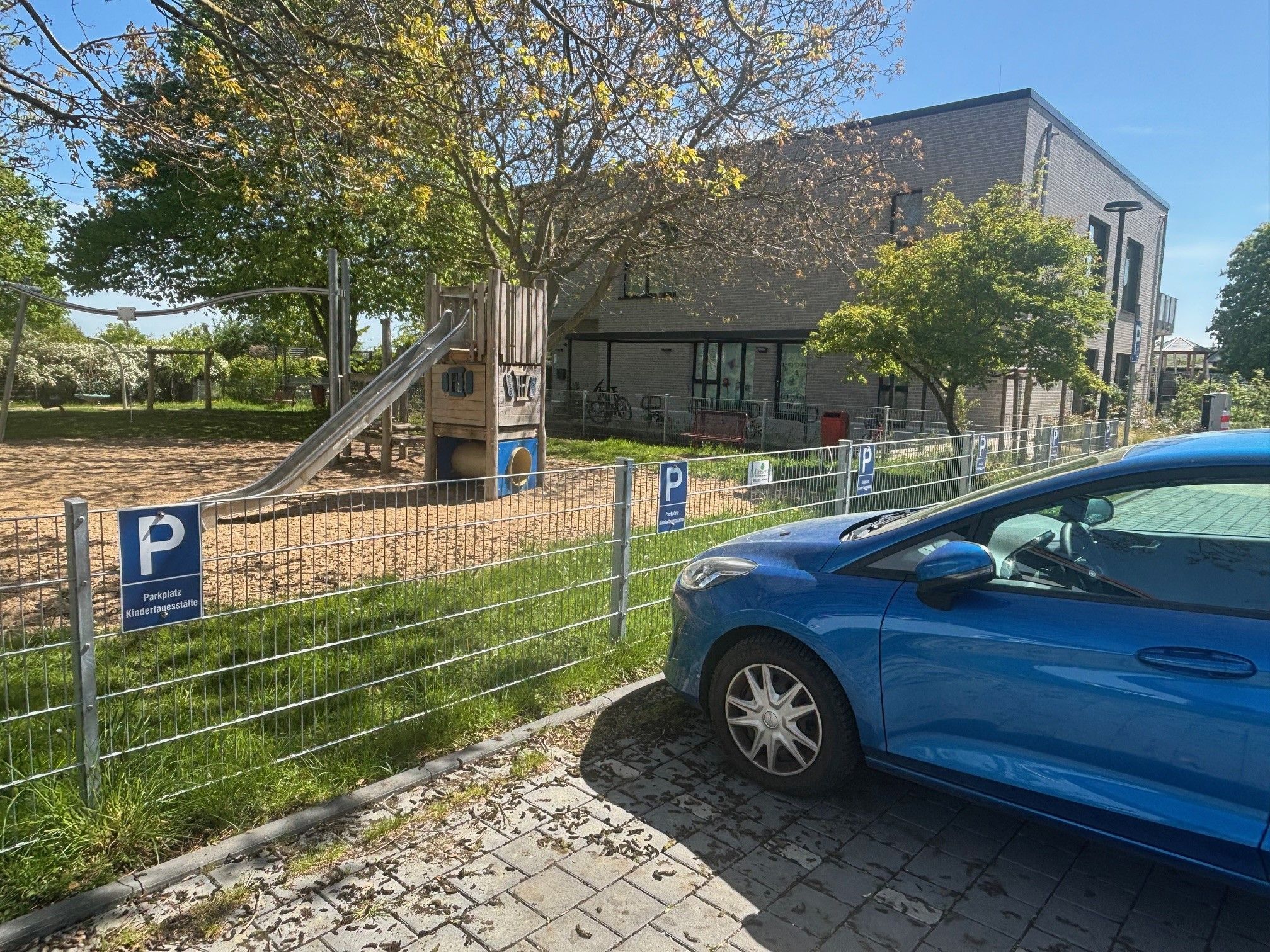 Auf einem Parkstreifen vor der Kita in Wißkirchen parkt ein blaues Auto.