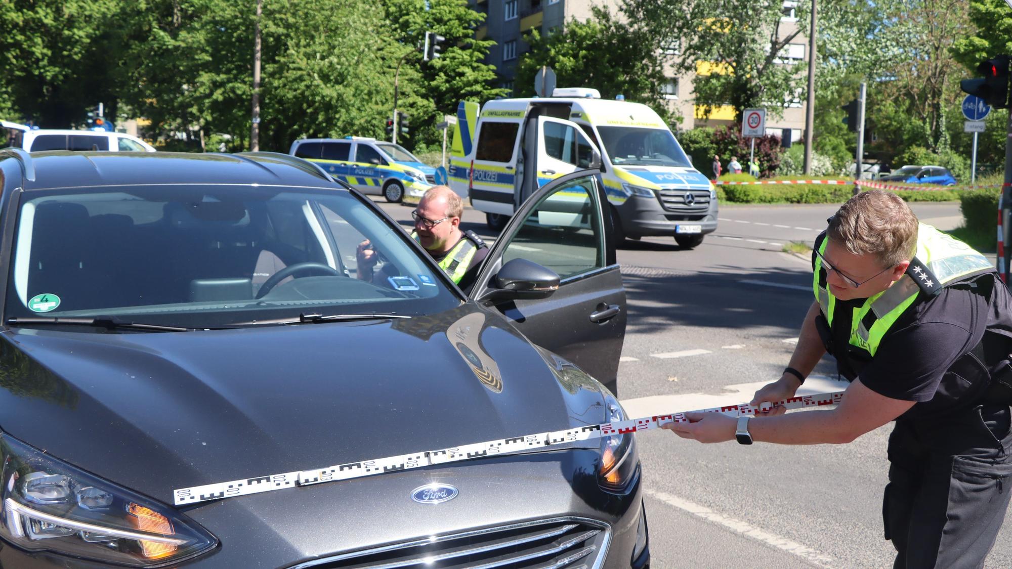 Das Bild zeigt zwei Polizisten an einem Auto. Die Beamten nehmen Spuren am Fahrzeug.