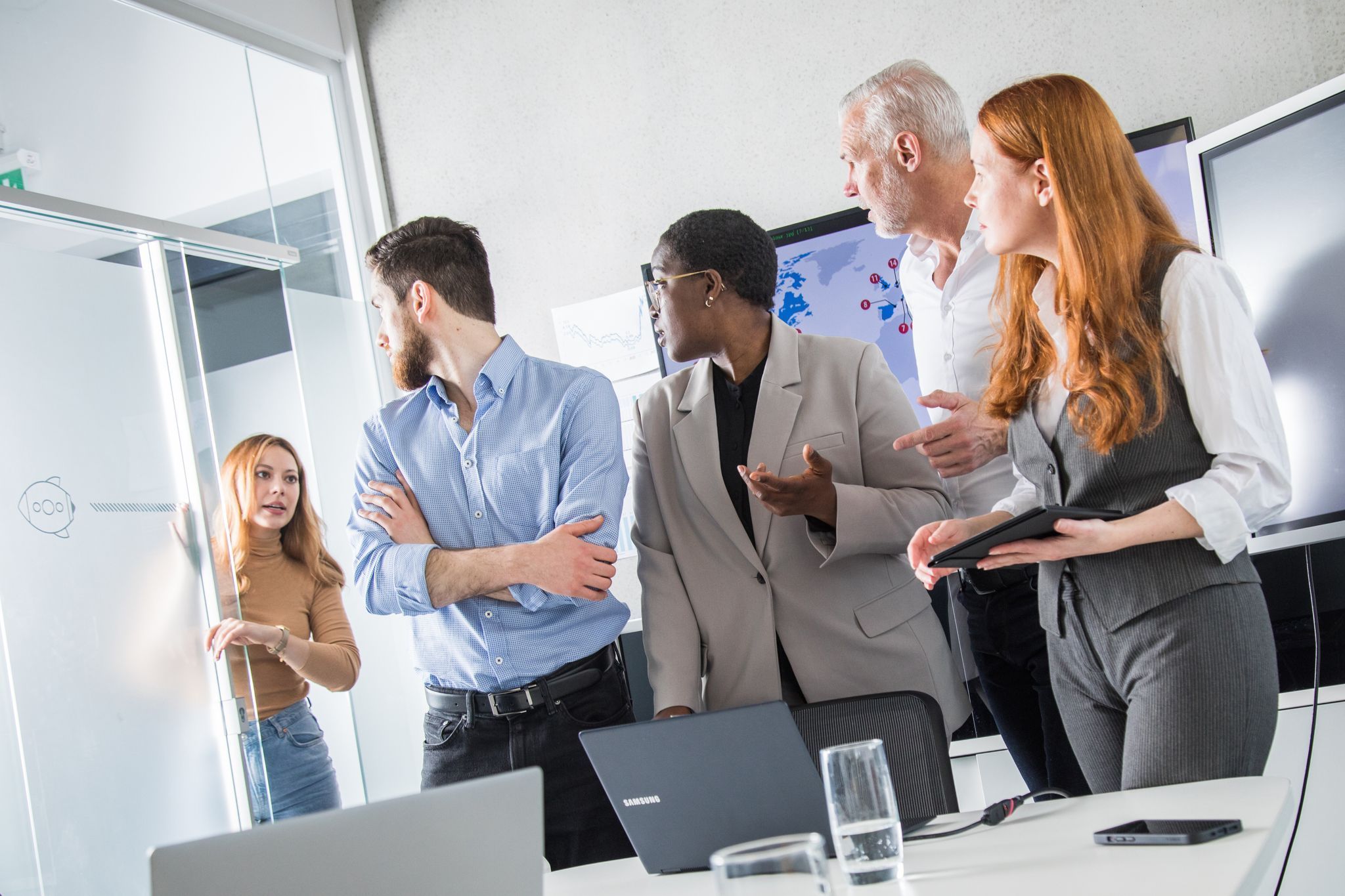 Eine Kollegin hebt die Uhr in einem Meeting mit anderen Kollegen