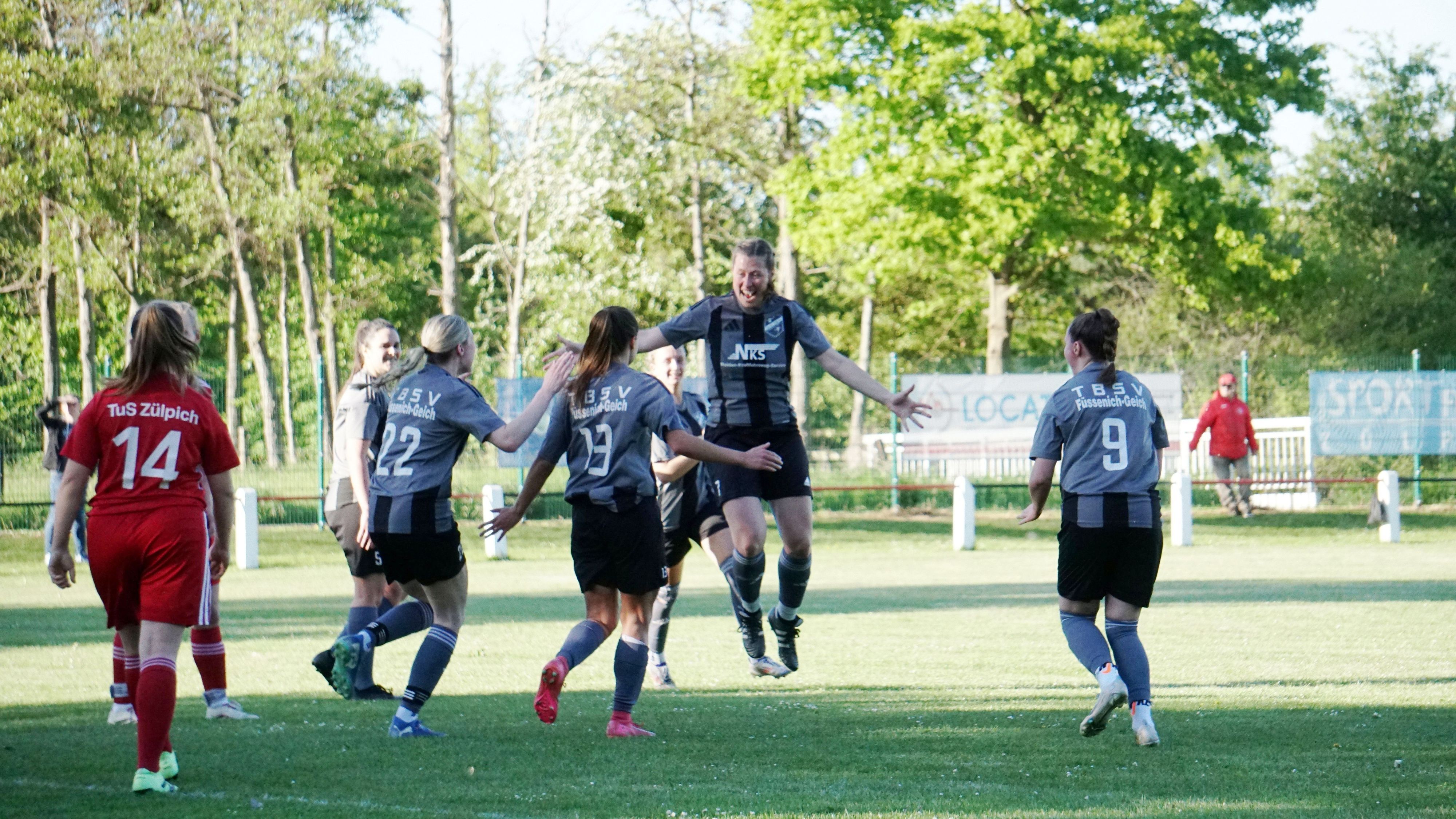 Eine Fußballerin springt nach einem erzielten Tor in die Luft. Mitspielerinnen laufen ihr entgegen.