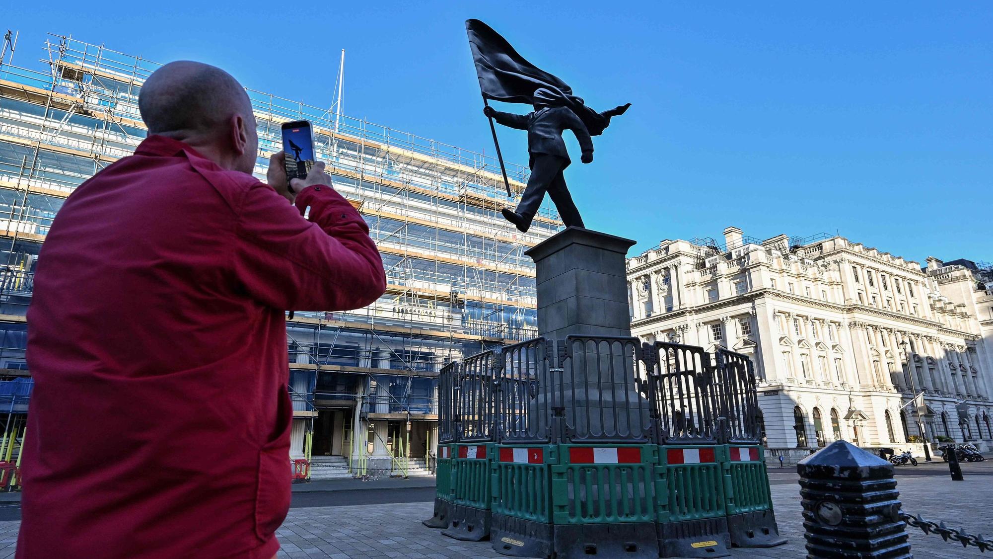 Am Waterloo Place im Zentrum Londons steht eine Statue, die einen Mann zeigt, der eine Flagge hält, die sein Gesicht verdeckt, und die am Sockel mit „Banksy“ unterzeichnet ist.