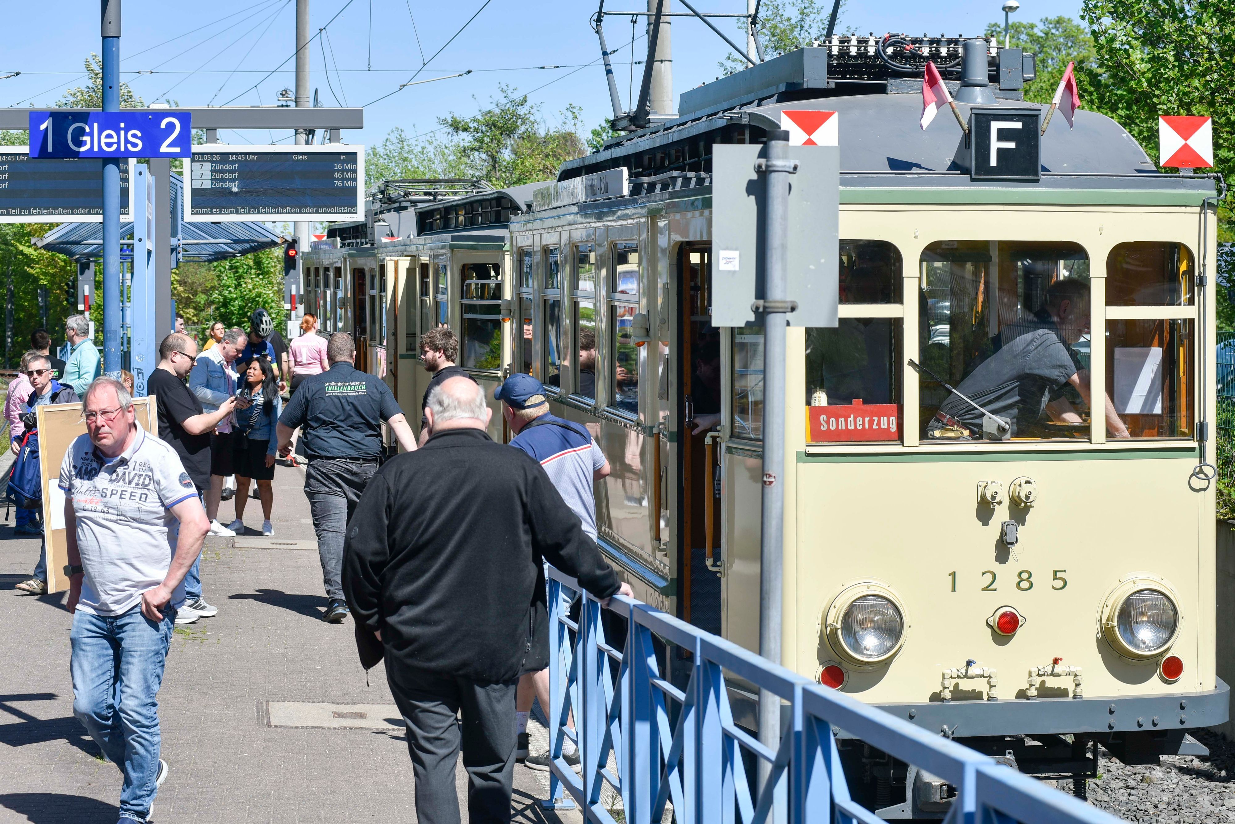 Auf dem Bild sind die historische Straßenbahn Finchen und Fahrgäste am Gleis zu sehen.