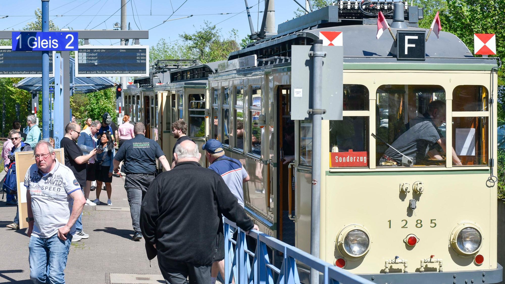 Auf dem Bild sind die historische Straßenbahn Finchen und Fahrgäste am Gleis zu sehen.