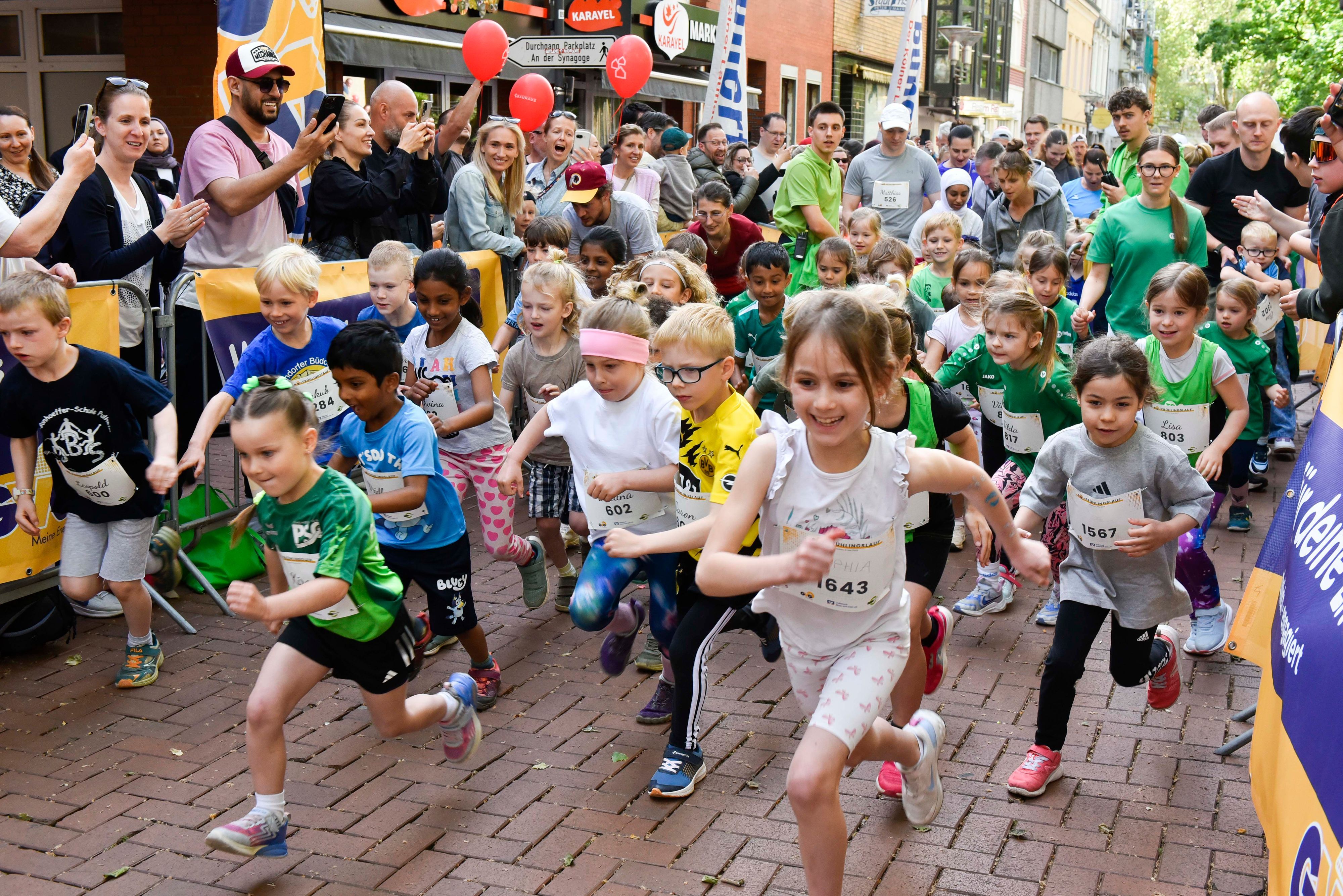Auf dem Bild sind Kindergartenkinder zu sehen, die vor Publikum zu einem Lauf starten.