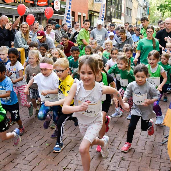 Auf dem Bild sind Kindergartenkinder zu sehen, die vor Publikum zu einem Lauf starten.