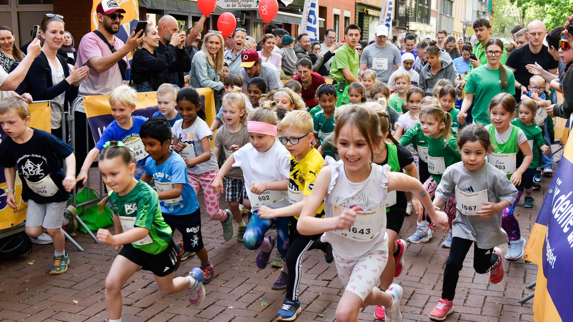 Auf dem Bild sind Kindergartenkinder zu sehen, die vor Publikum zu einem Lauf starten.