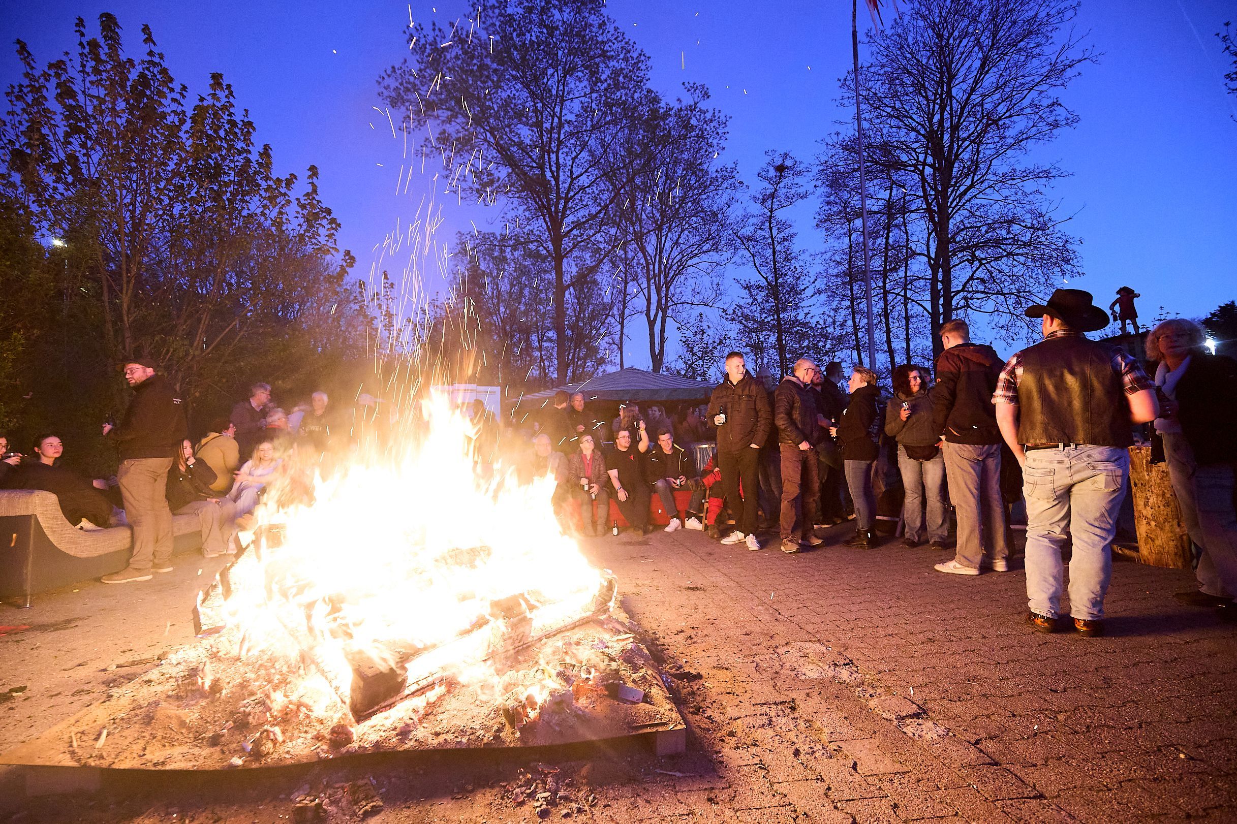 Um das hell lodernde Feuerwehr haben sich viele junge Leute geschart.