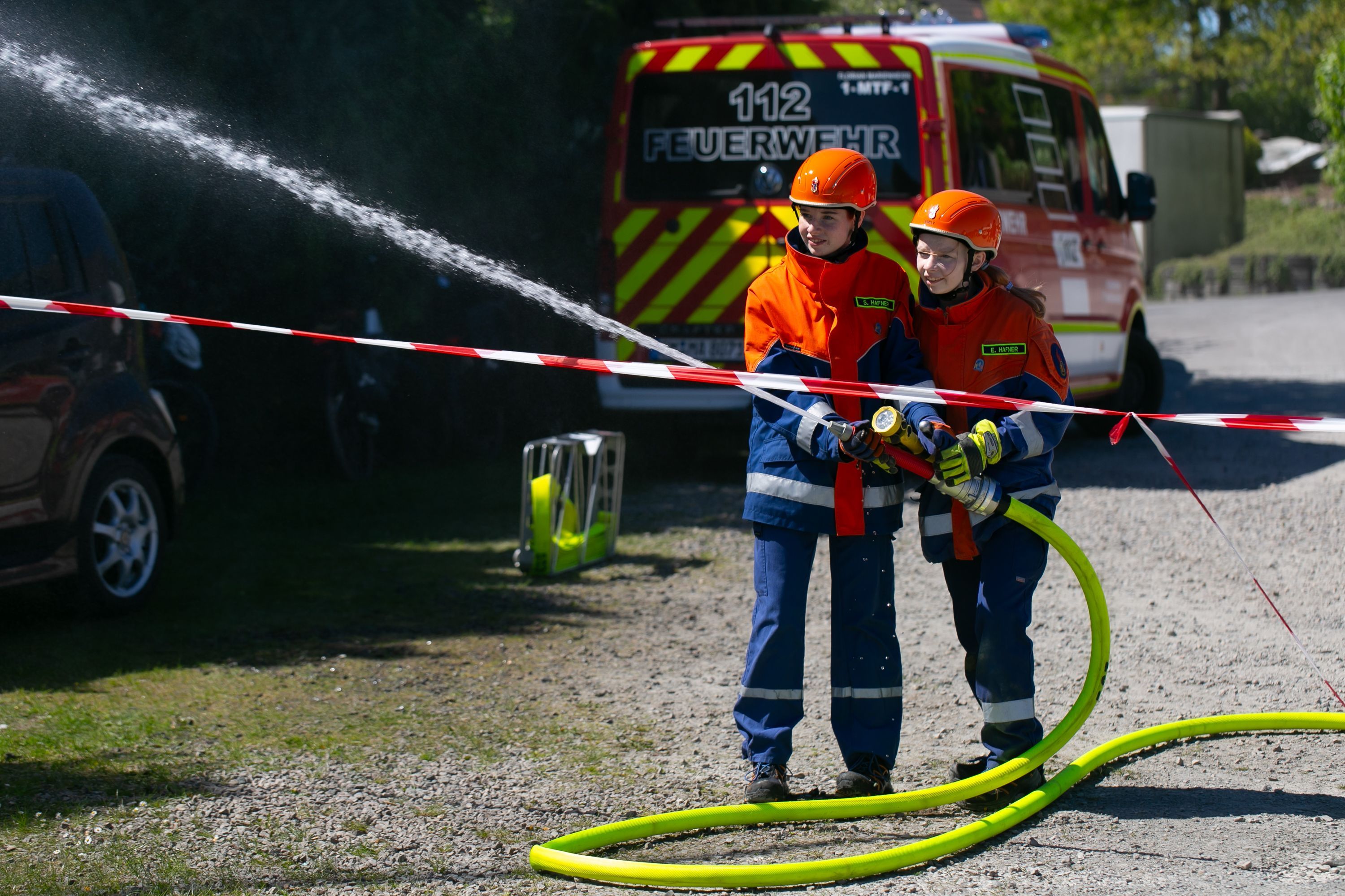 Eine Schauübung zweier Kinder der Kinderfeuerwehr, die mit einem Schlauch löschen.