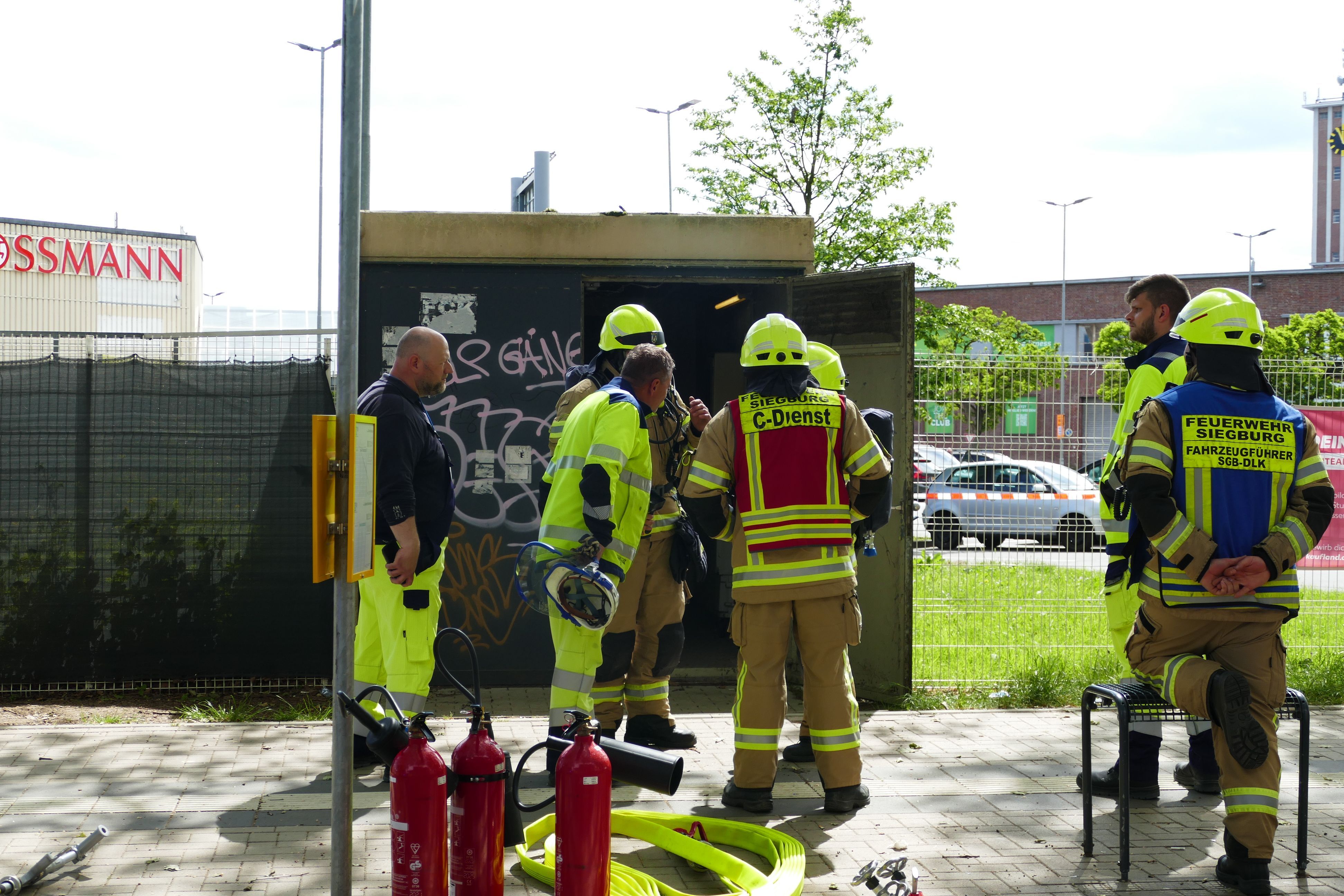 Hier lag offenbar die Ursache: Feuerwehrleute und Westnetz-Mitarbeiter stehen vor der Mittelspannungsschaltstelle an der Wilhelm-Oswald-Straße.