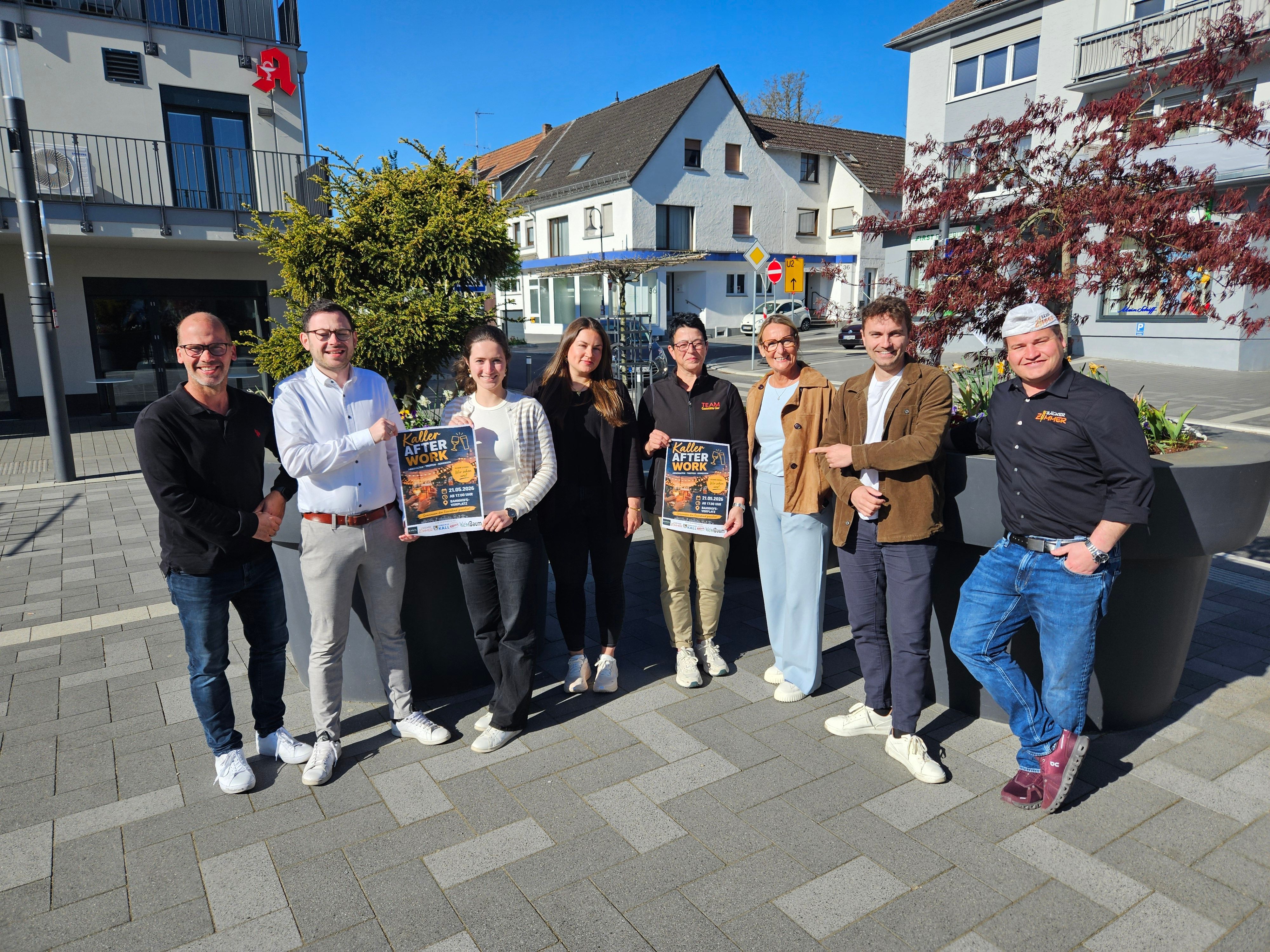 Vier Männer und vier Frauen stehen auf dem Bahnhofsvorplatz nebeneinander und präsentieren zwei Plakate.