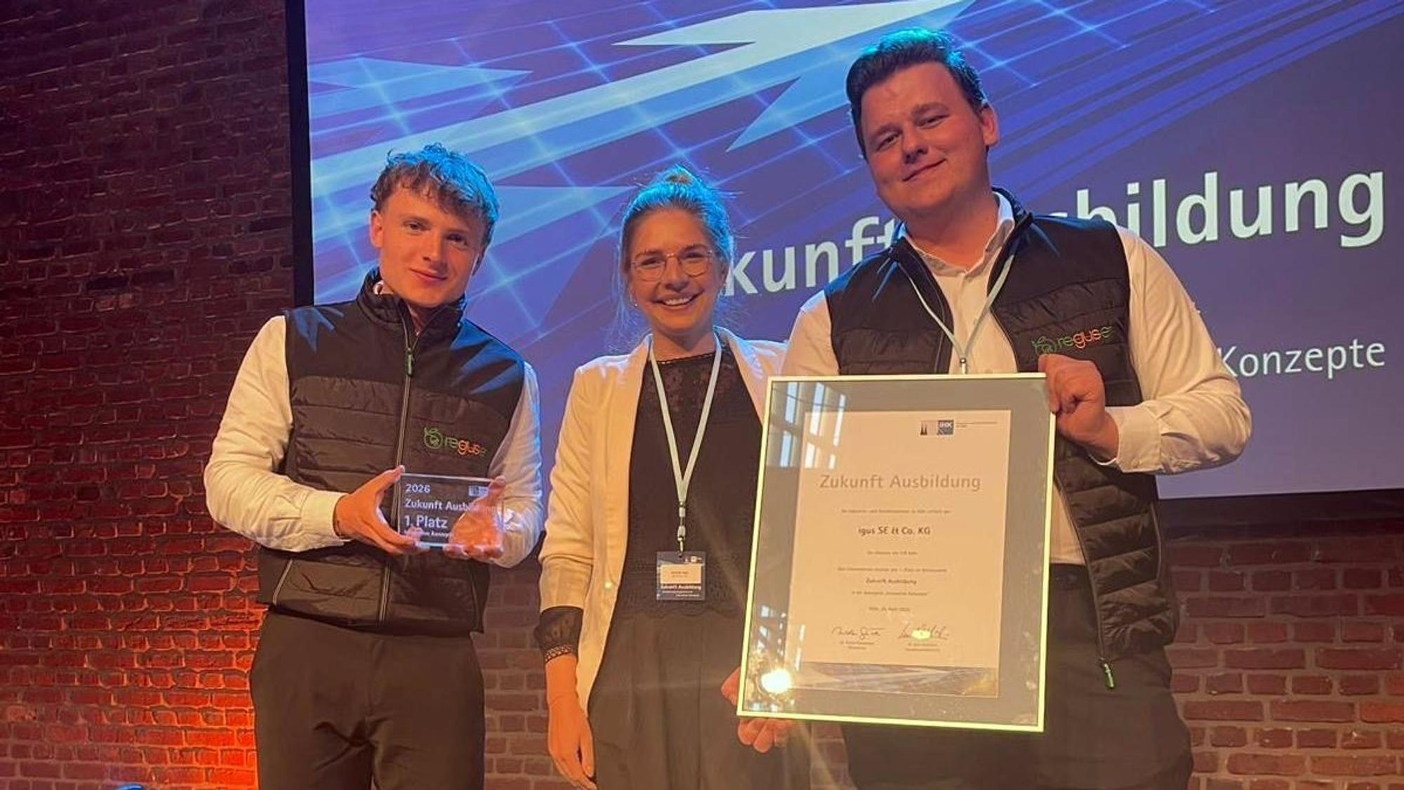 Leander Plum (l.) und Noah Smieskol (r.), beide duale Studenten bei Igus, nahmen gemeinsam mit ihrer Ausbildungsleiterin Michelle Haas (M.) den IHK-Preis „Zukunft Ausbildung“ für das Reguse-Projekt entgegen.