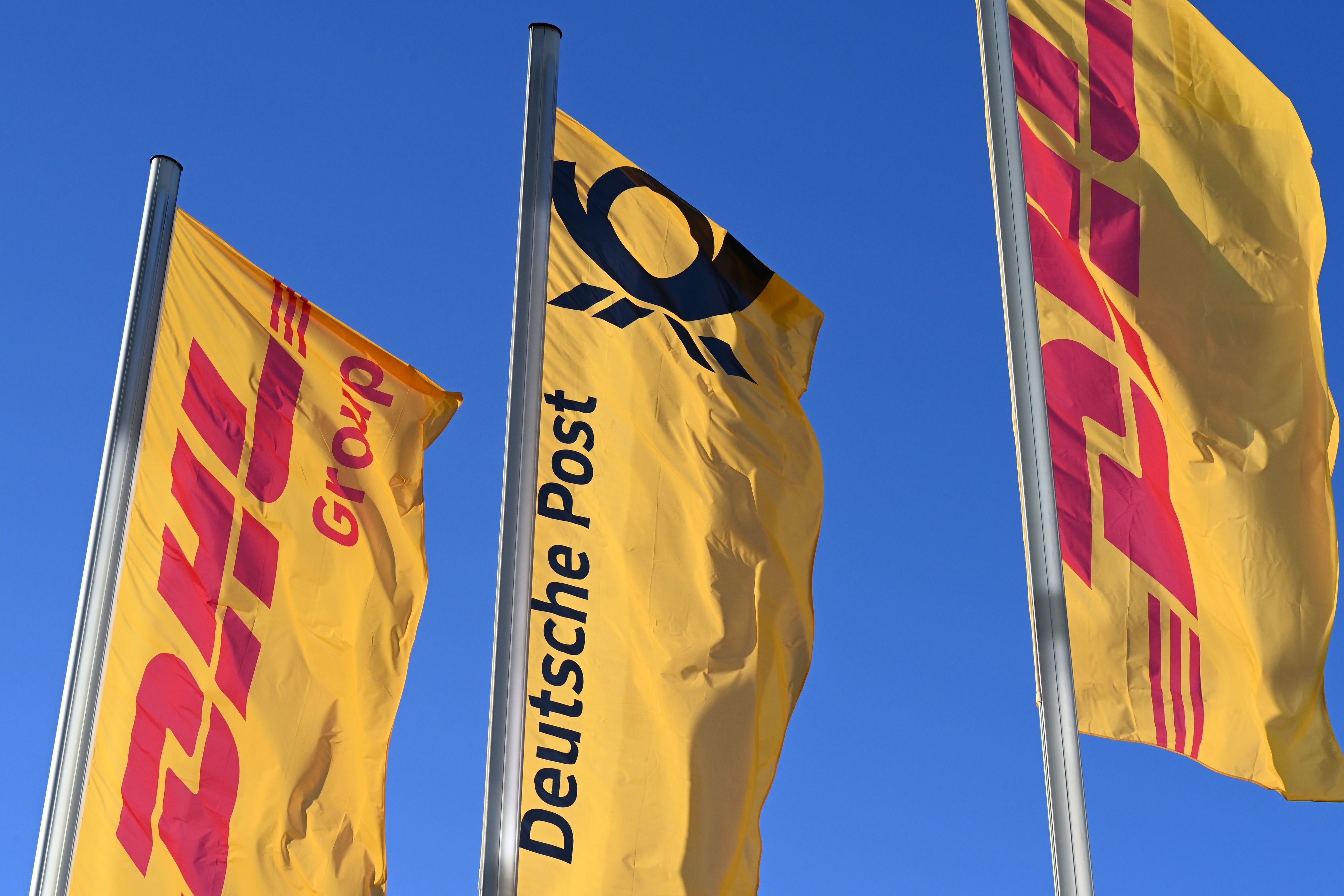 Fahnen des Logistikkonzerns DHL und seiner Brieftochter Deutsche Post wehen vor der Konzernzentrale an Masten. Der Konzern möchte sich von Deutsche Post AG zu DHL AG umbenennen.