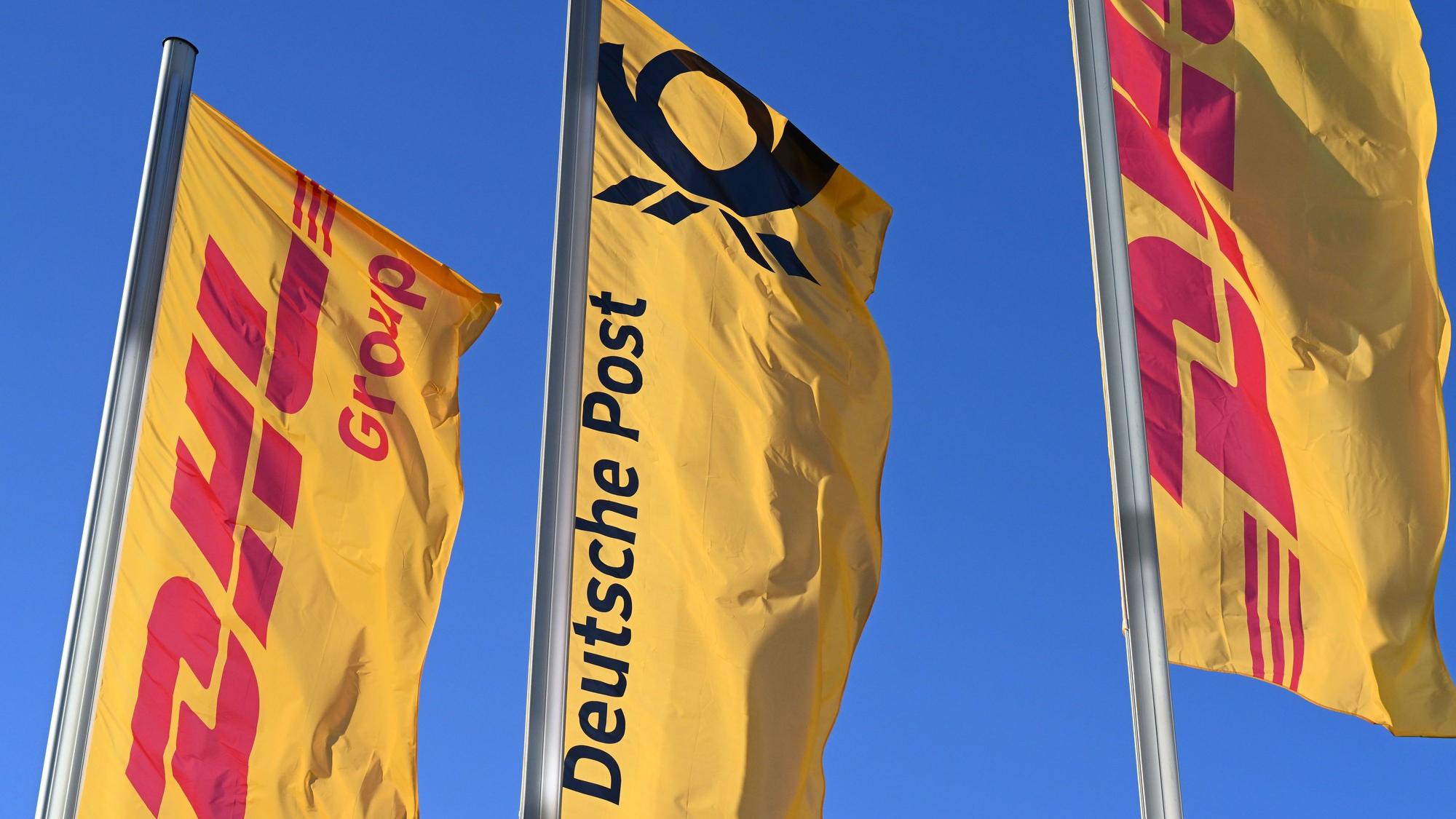Fahnen des Logistikkonzerns DHL und seiner Brieftochter Deutsche Post wehen vor der Konzernzentrale an Masten. Der Konzern möchte sich von Deutsche Post AG zu DHL AG umbenennen.