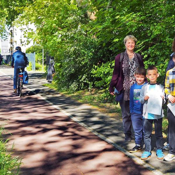 Drei Kinder und zwei Frauen stehen am Rand eines Radwegs.